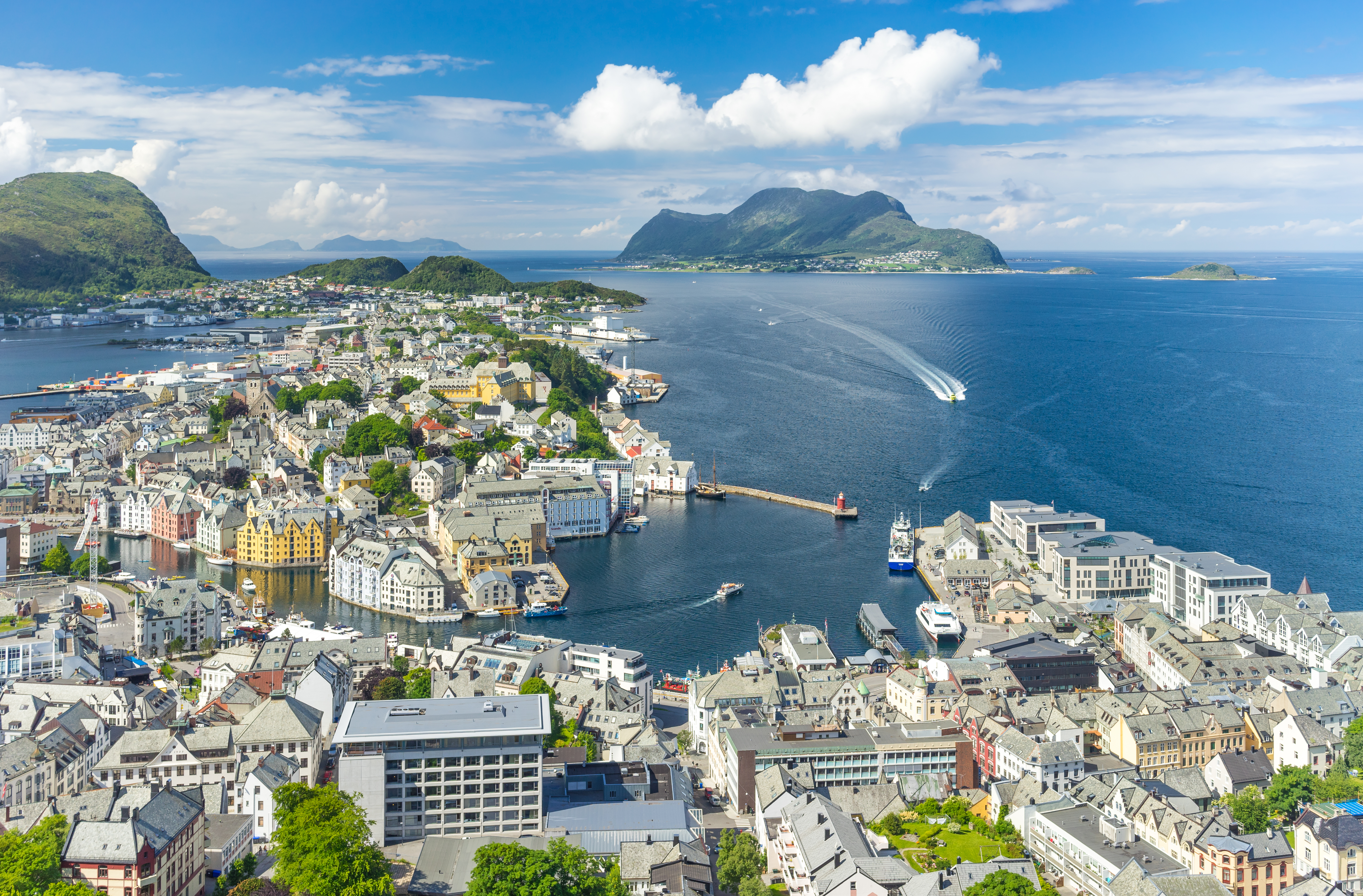 Udsigt fra Aksla-udsigtspunktet over Ålesund i Norge med havnen, de hvide og farverige huse og grønne bjerge ved havet