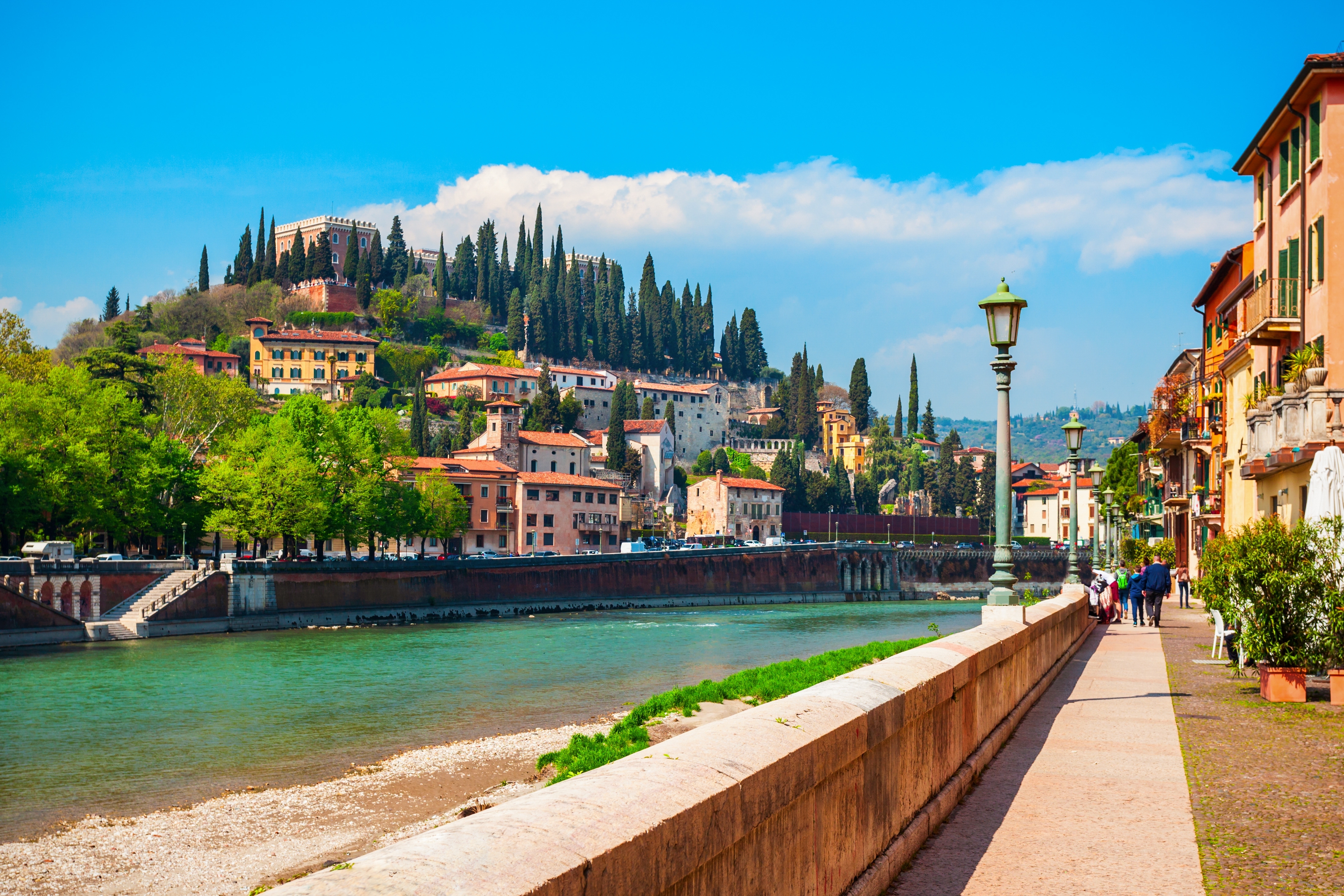 Charmerende flodpromenade langs Adige-floden med udsigt til San Pietro-borgen og de karakteristiske bygninger i Verona