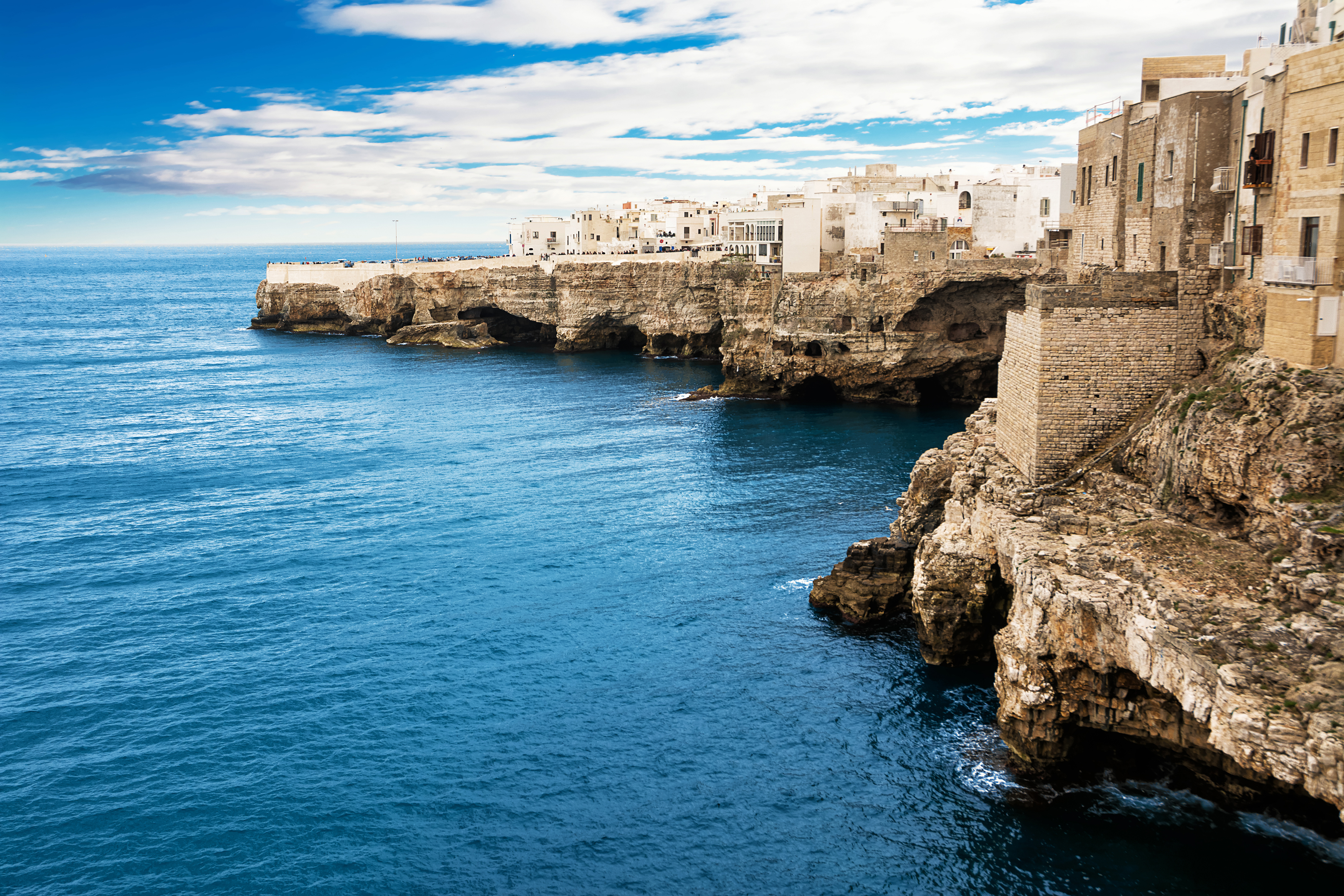 Dramatisk kystlandskab i Polignano a Mare hvor historiske bygninger møder det azurblå Adriaterhav på Puglia's klippekyst