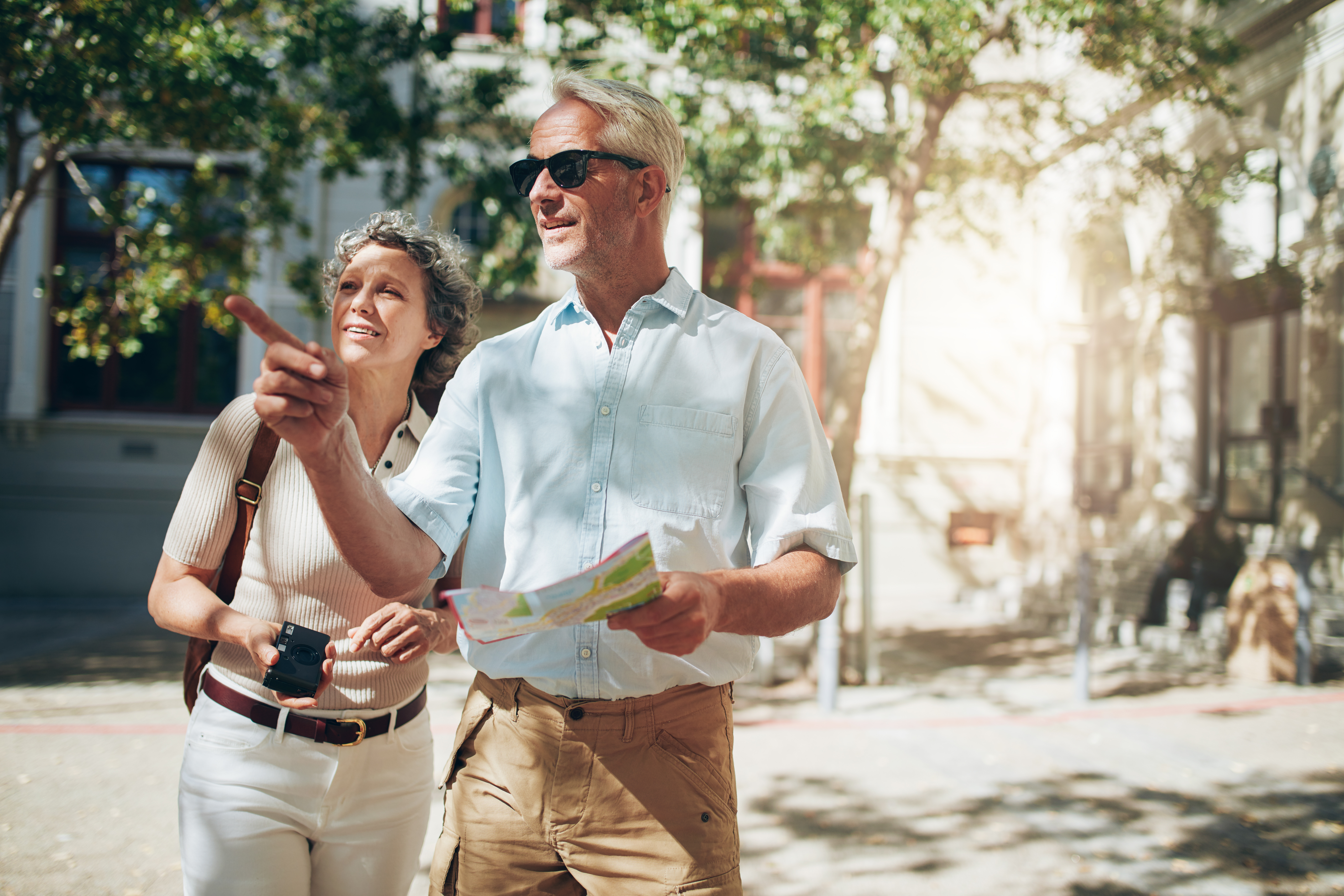 Aeldre par paa turisttur med kort i europaeisk by om sommeren
