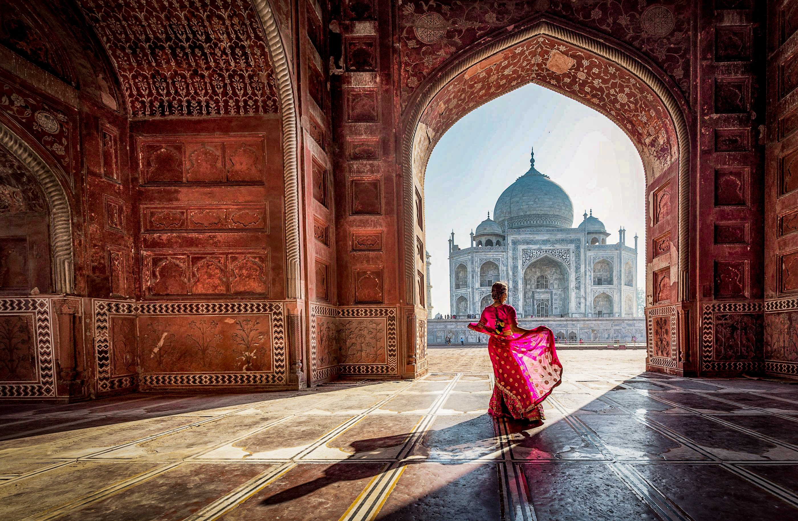 Kvinde i farverig sari ved Taj Mahals islamiske arkitektur i Agra