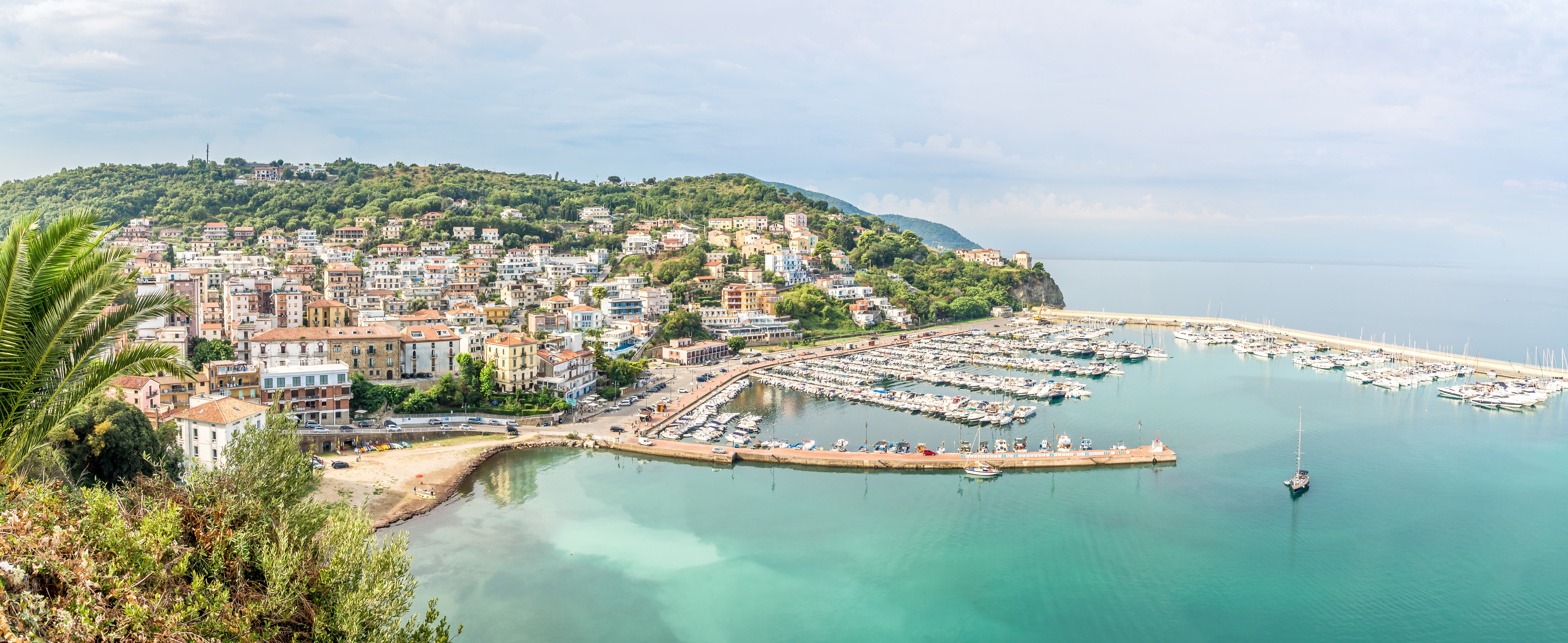 Panoramabillede af Agropoli i Italien med den smukke marina, turkisblåt middelhavsvand og pittoreske bygninger langs den grønne bakkeskråning