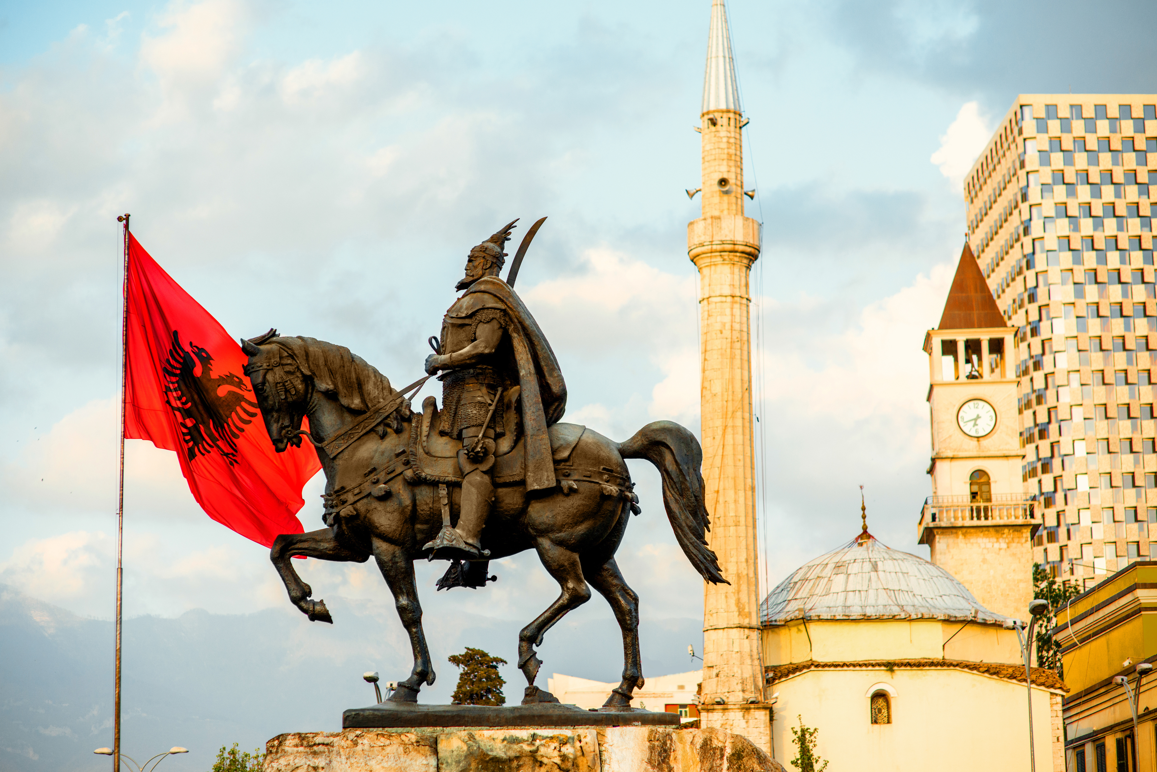 Monument af Albaniens nationalhelt Skanderbeg med det albanske flag i Tiranas centrum, omgivet af historiske bygninger