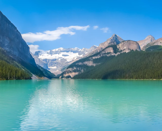 Idyllisk sommerudsigt over den smukke Lake Louise med sin karakteristiske turkise farve, omgivet af majestætiske bjerge og grønne skove i Banff National Park, Alberta, Canada