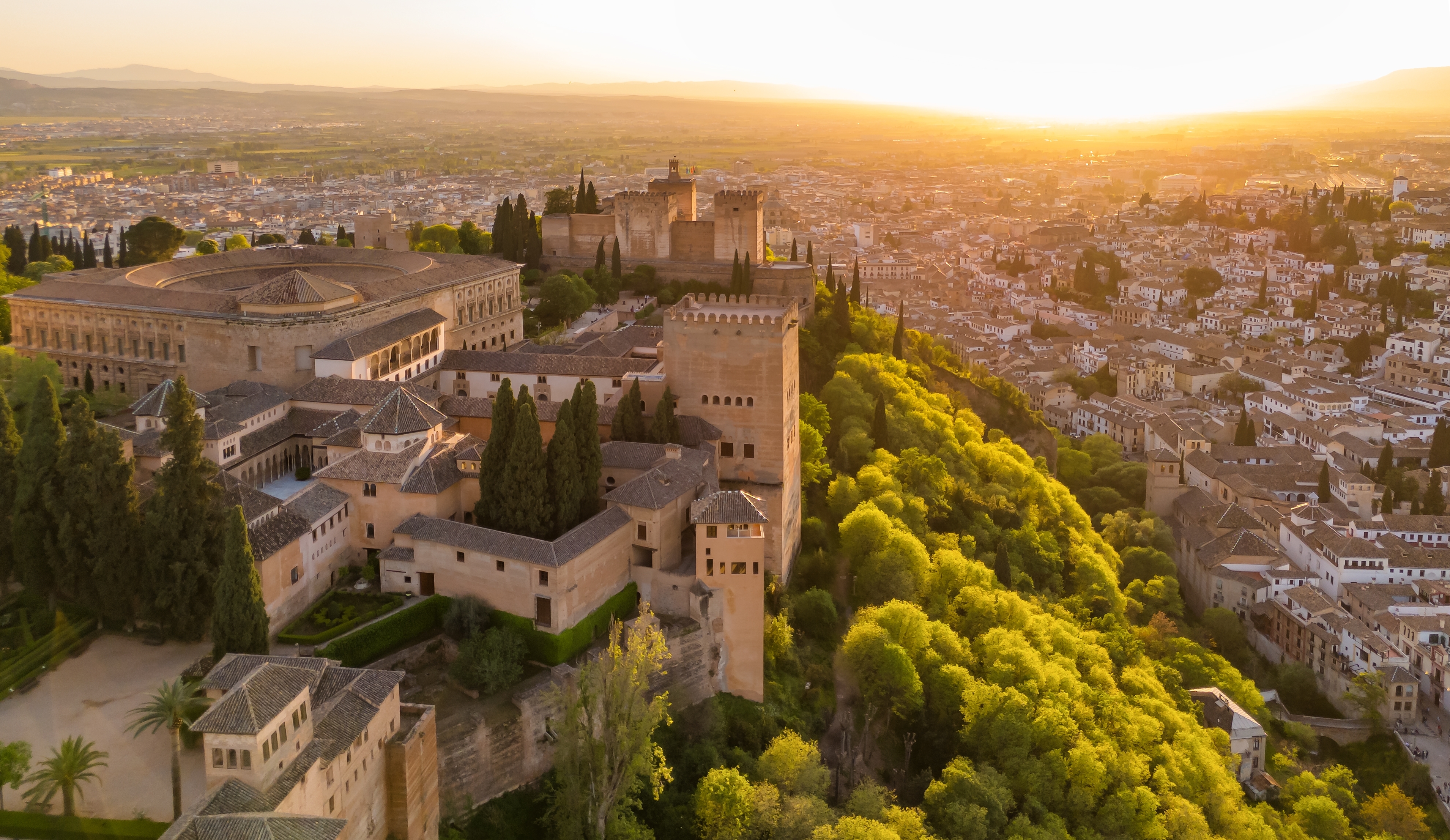 Dronefoto af den historiske Alhambra-fæstning og det mauriske palads ved solnedgang i Granada, Andalusien
