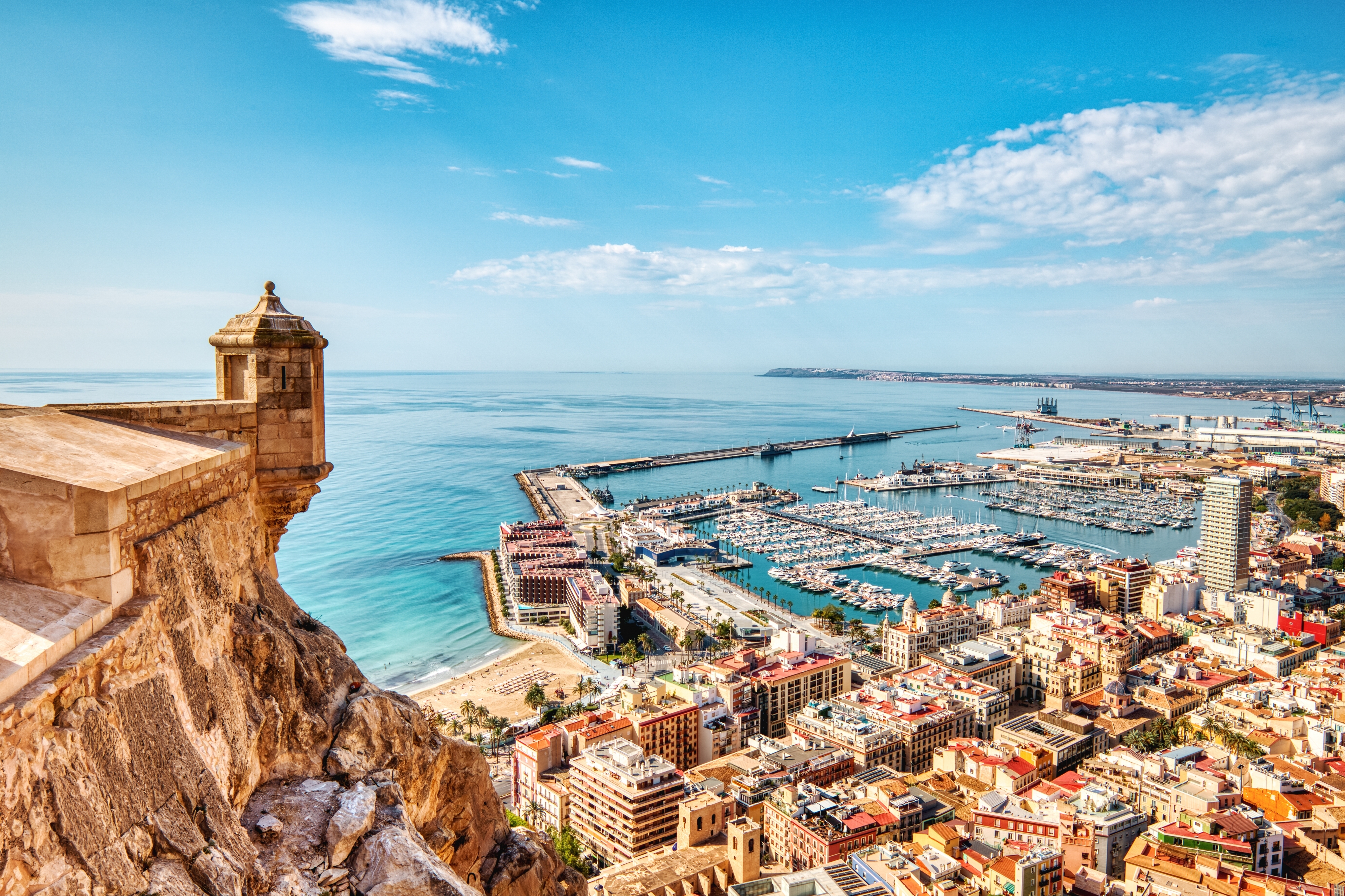 Imponerende luftfoto af Santa Barbara-slottet og Alicantes havn med lystbåde og den turkisblå Middelhavskyst i Spanien