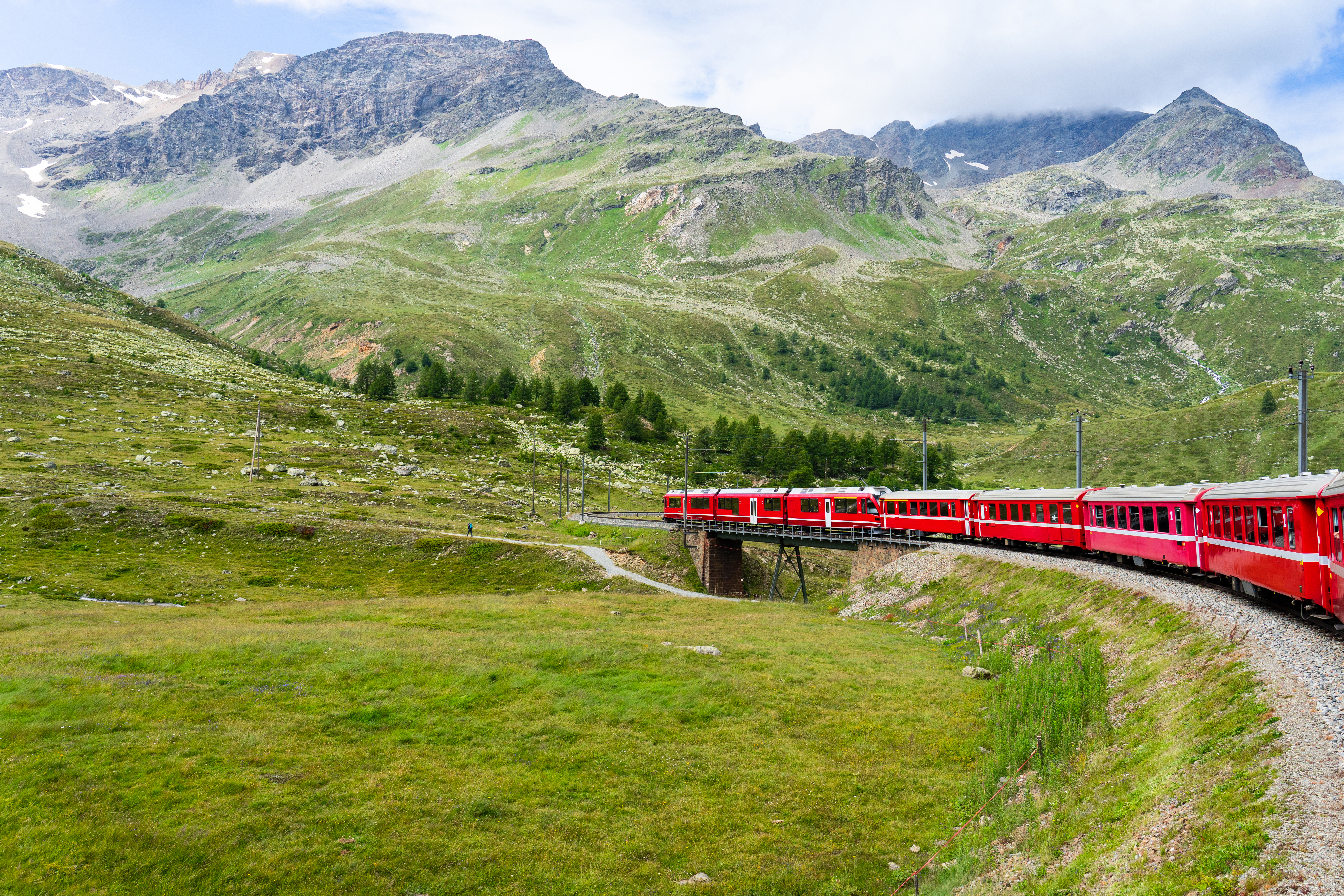 Alpetog i Schweiz kører gennem bjerglandskab med gletsjere og grønne skråninger