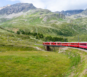 Alpetog i Schweiz kører gennem bjerglandskab med gletsjere og grønne skråninger