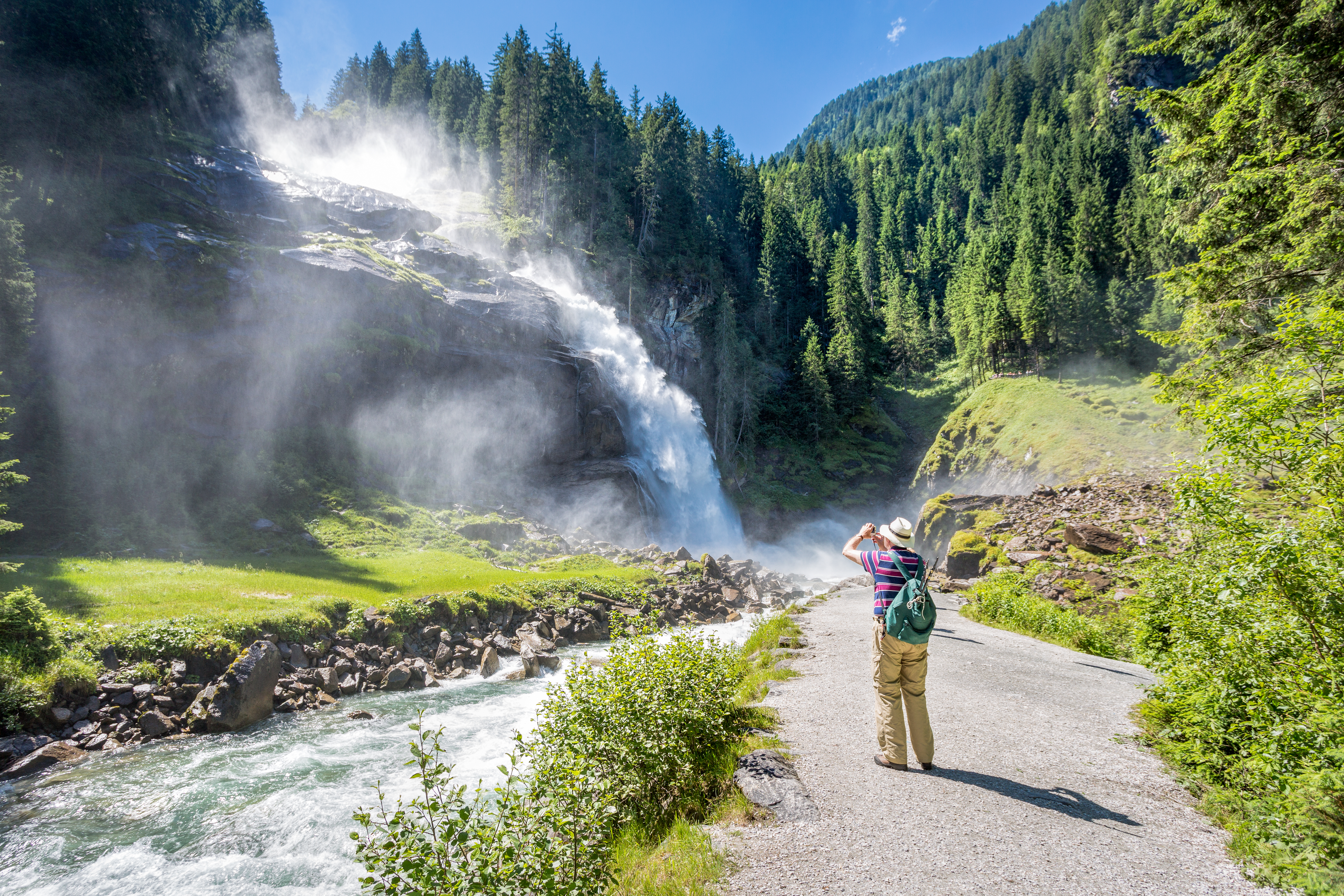 Naturelskende turist ved imponerende alpevandfald i Østrig med grønne skove