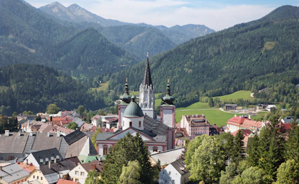 Pittoresk udsigt over Mariazell med barok basilika og gotisk kirketårn i østrigske alper