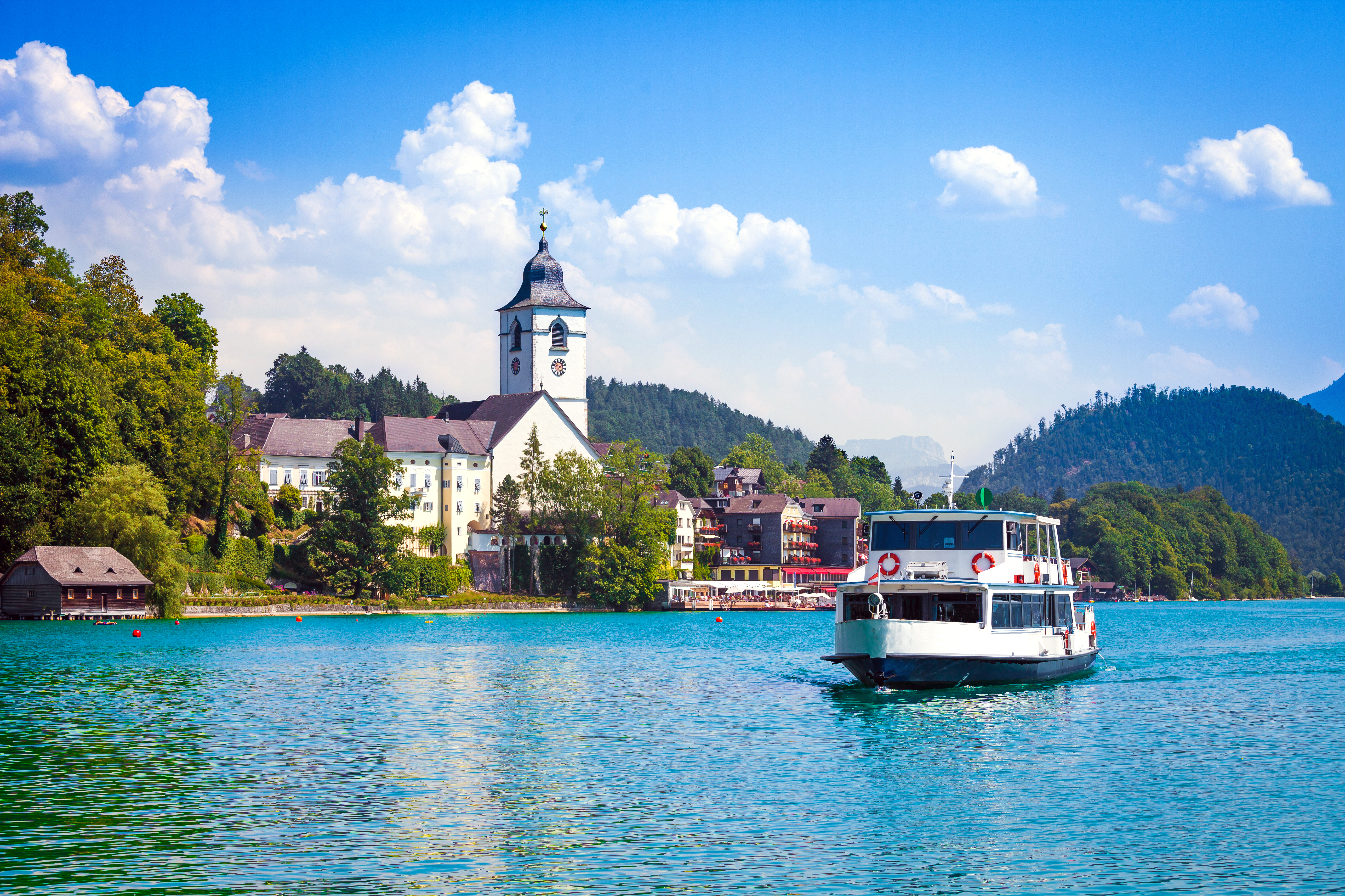 Fantastisk alpelandskab ved Wolfgangsee med karakteristisk kirke og sightseeing båd