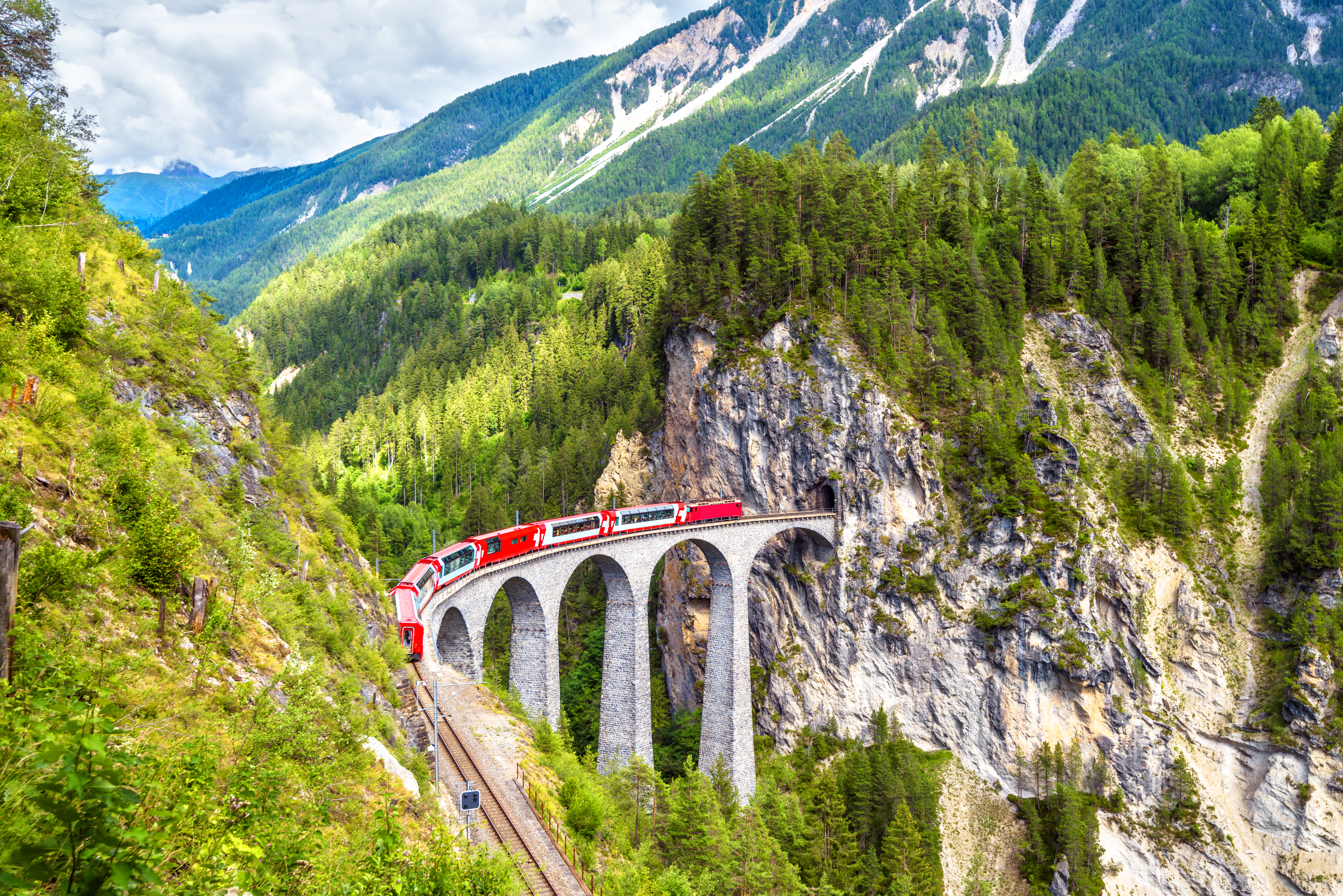 Luftfoto af den berømte Gletsjer-ekspressen der kører over den historiske Landwasser Viadukt med smuk alpeudsigt