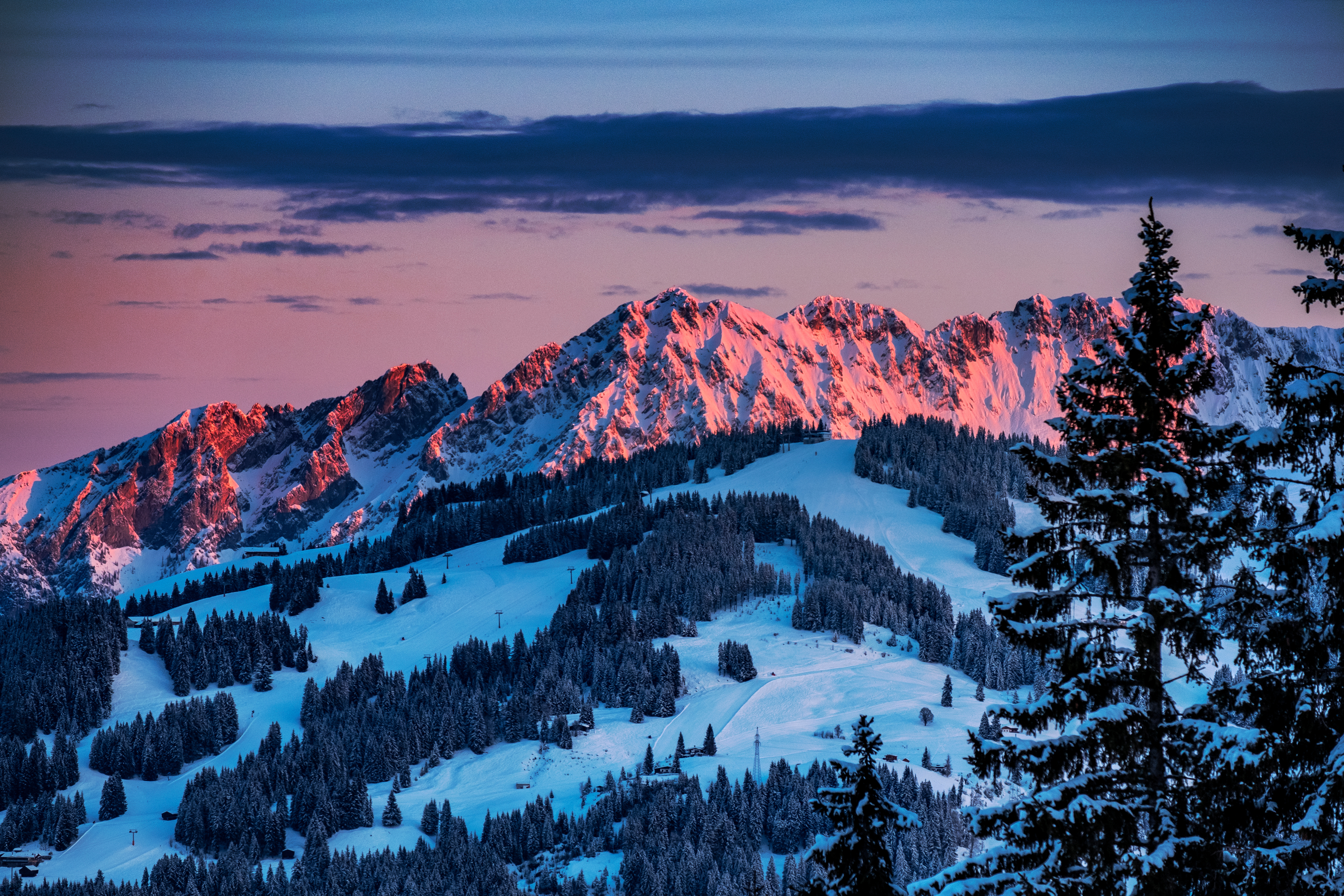 Fantastisk alpinudsigt over Westendorf i Tyrol, Østrig med rosa alpengløde på snedækkede bjergtinder ved solnedgang