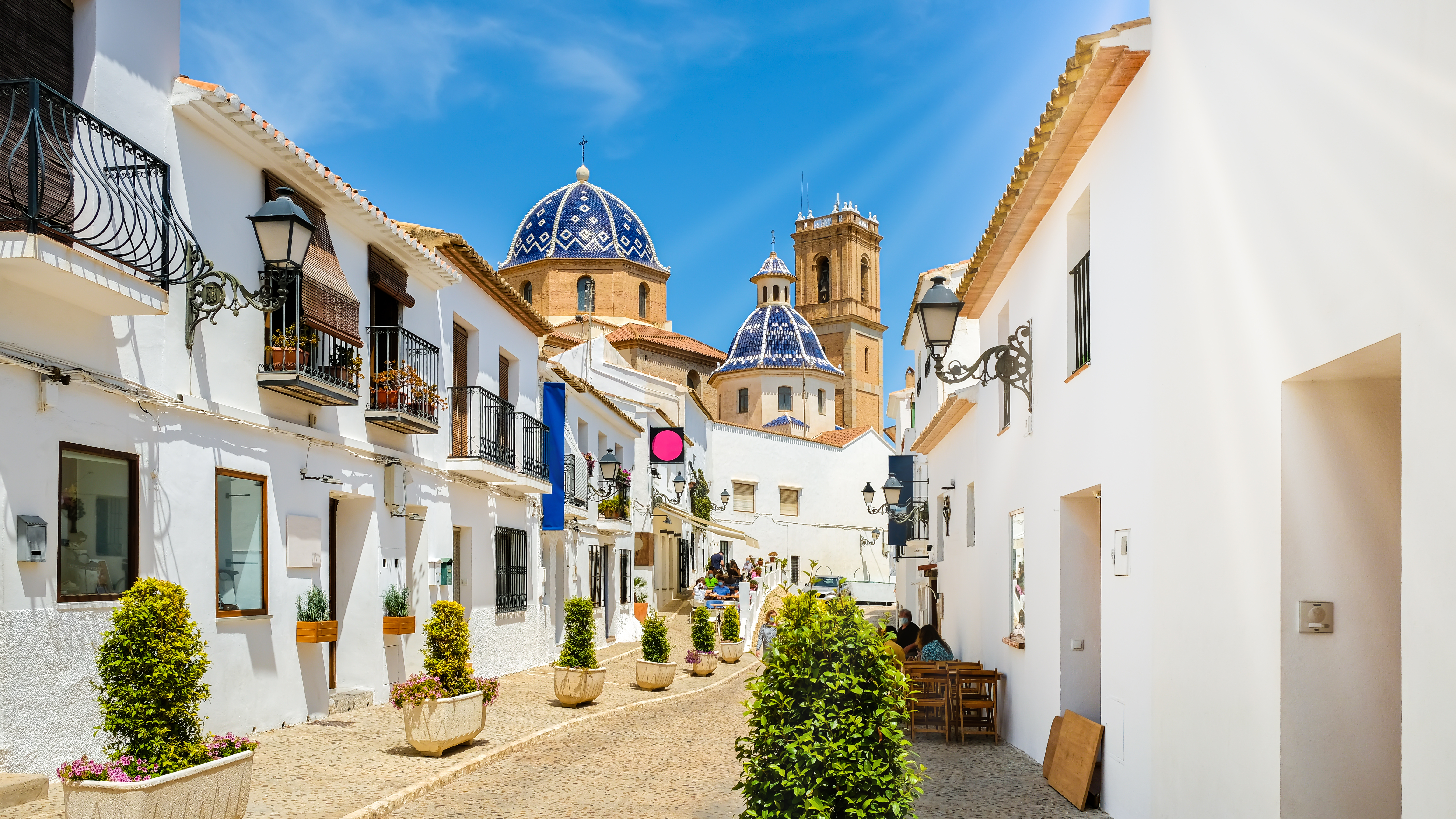 Pittoresk gade i Alteas gamle kvarter med traditionelle hvide huse og den iøjnefaldende blå kuppelkirke, en autentisk spansk oplevelse ved Costa Blanca