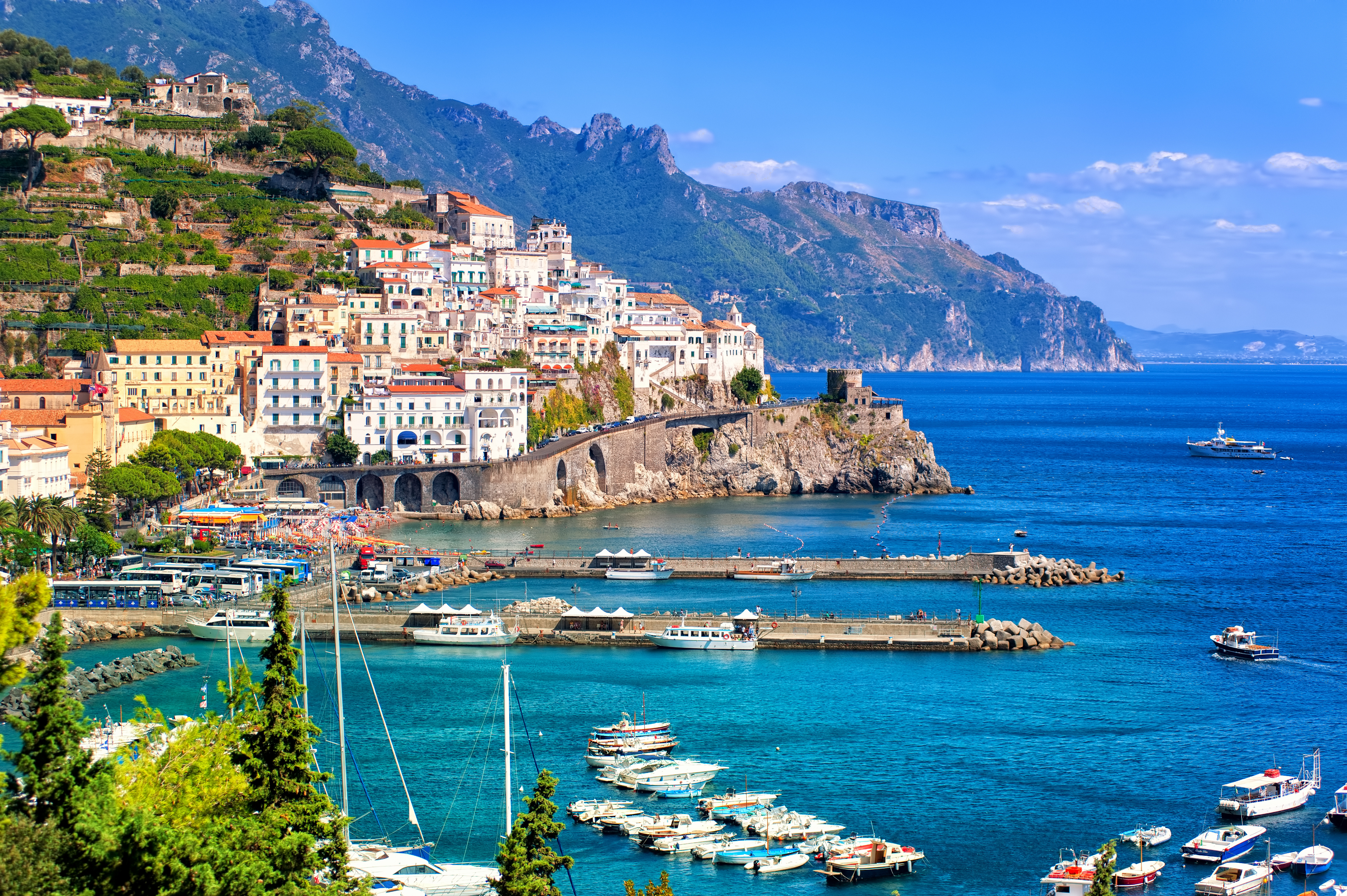 Udsigt over den smukke kystby Amalfi ved Salerno i Syditalien med hvide og gule bygninger ned mod det klare turkisblå hav og en travl lystbådehavn