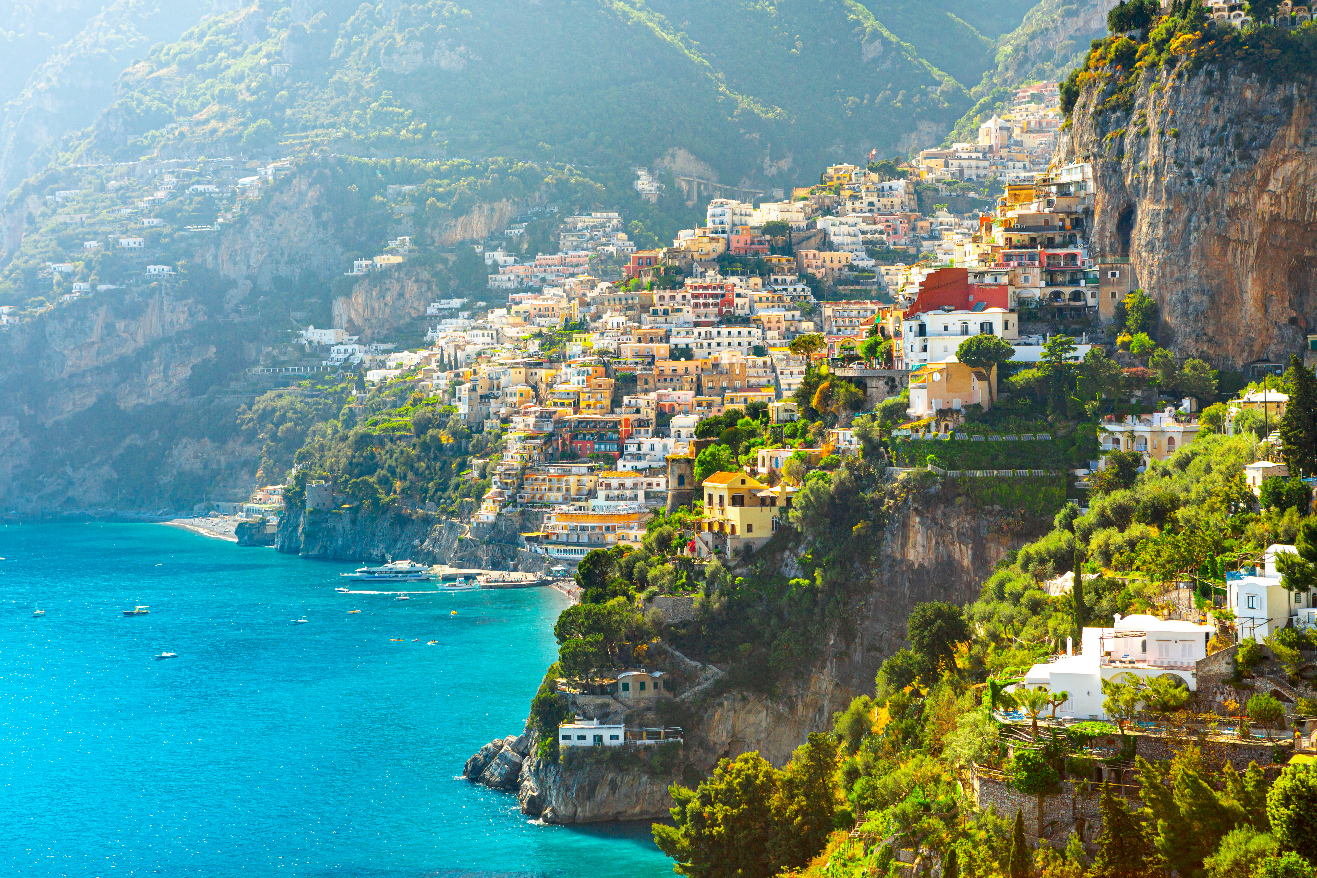 Spektakulær morgenudsigt over den ikoniske by Positano, med dens farvestrålende bygninger der skråner ned mod den azurblå Middelhavskyst på den romantiske Amalfirute i Italien
