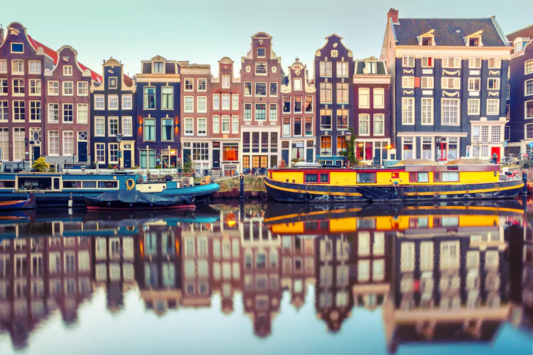 Pittoreske Amsterdam kanalhuse og både med perfekte vandrefleksioner i Holland