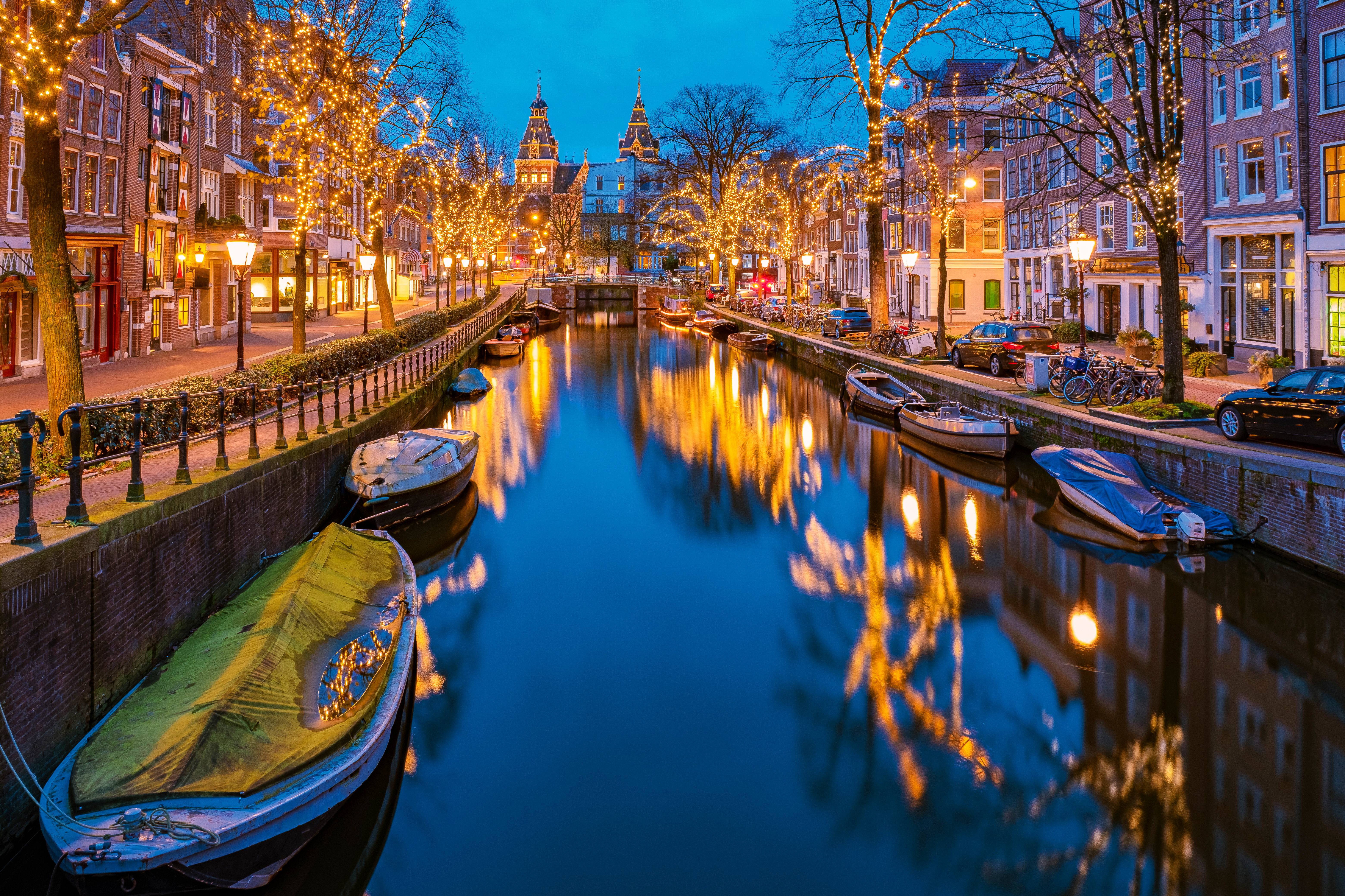 Smuk Amsterdam-kanal med julelys og både der skaber magiske refleksioner