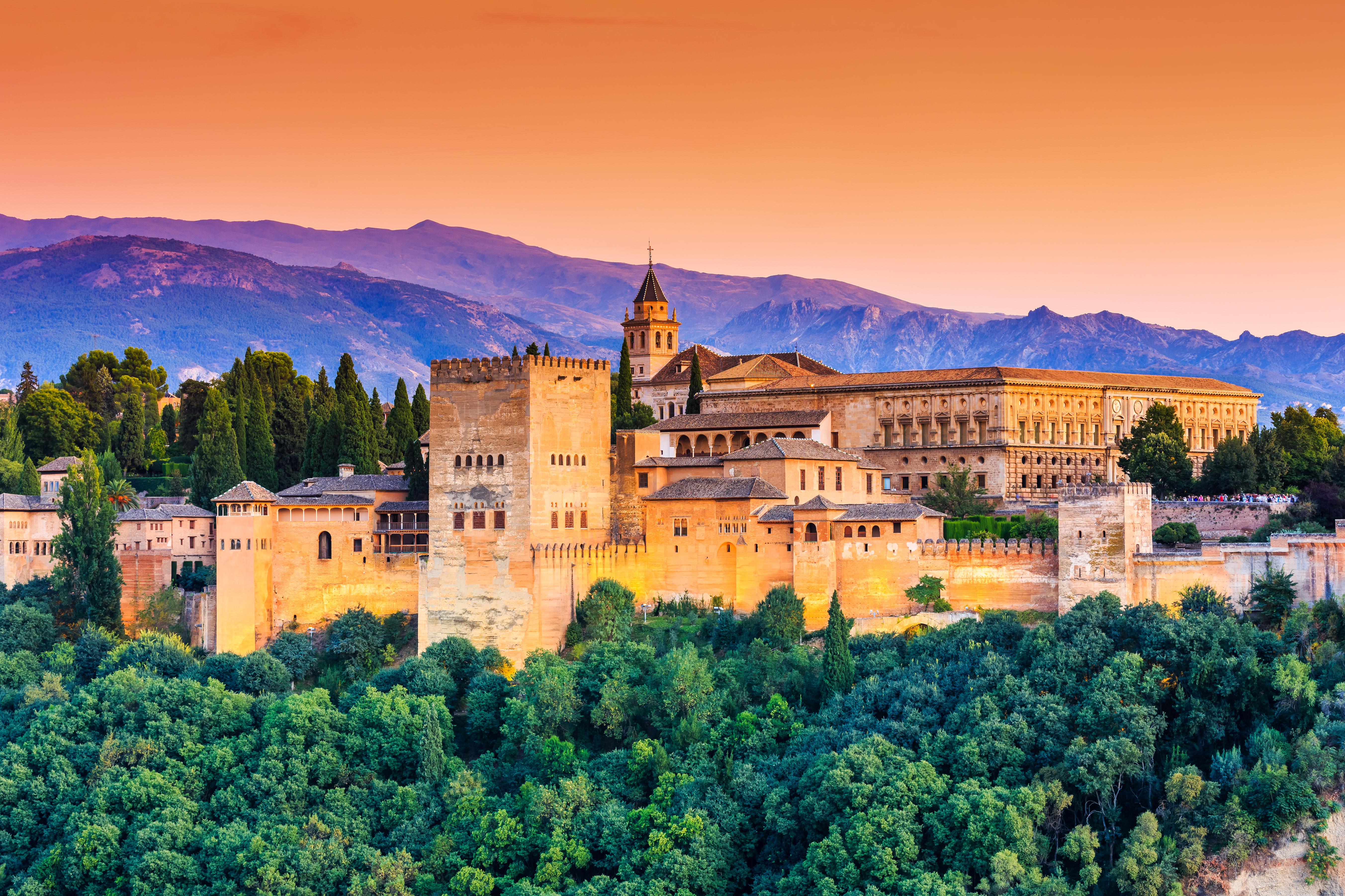 Den mauriske Alhambra-fæstning i Granada med Sierra Nevada-bjergene, badet i solnedgangens orange skær, Andalusien, Spanien