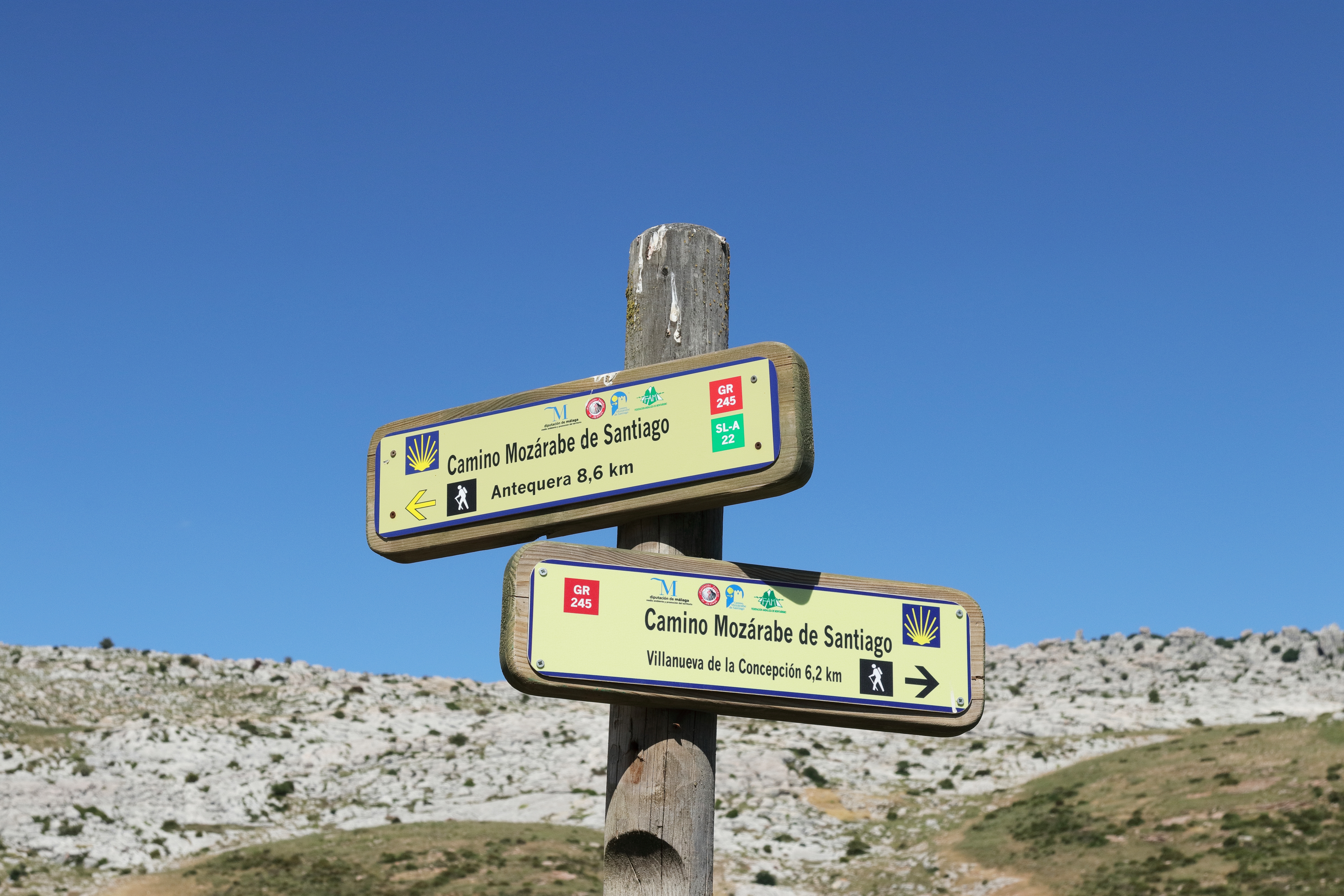 Vejviserskilt på den historiske Camino Mozarabe pilgrimsrute i Andalusien, en af de ældste ruter mod Santiago de Compostela under blå himmel