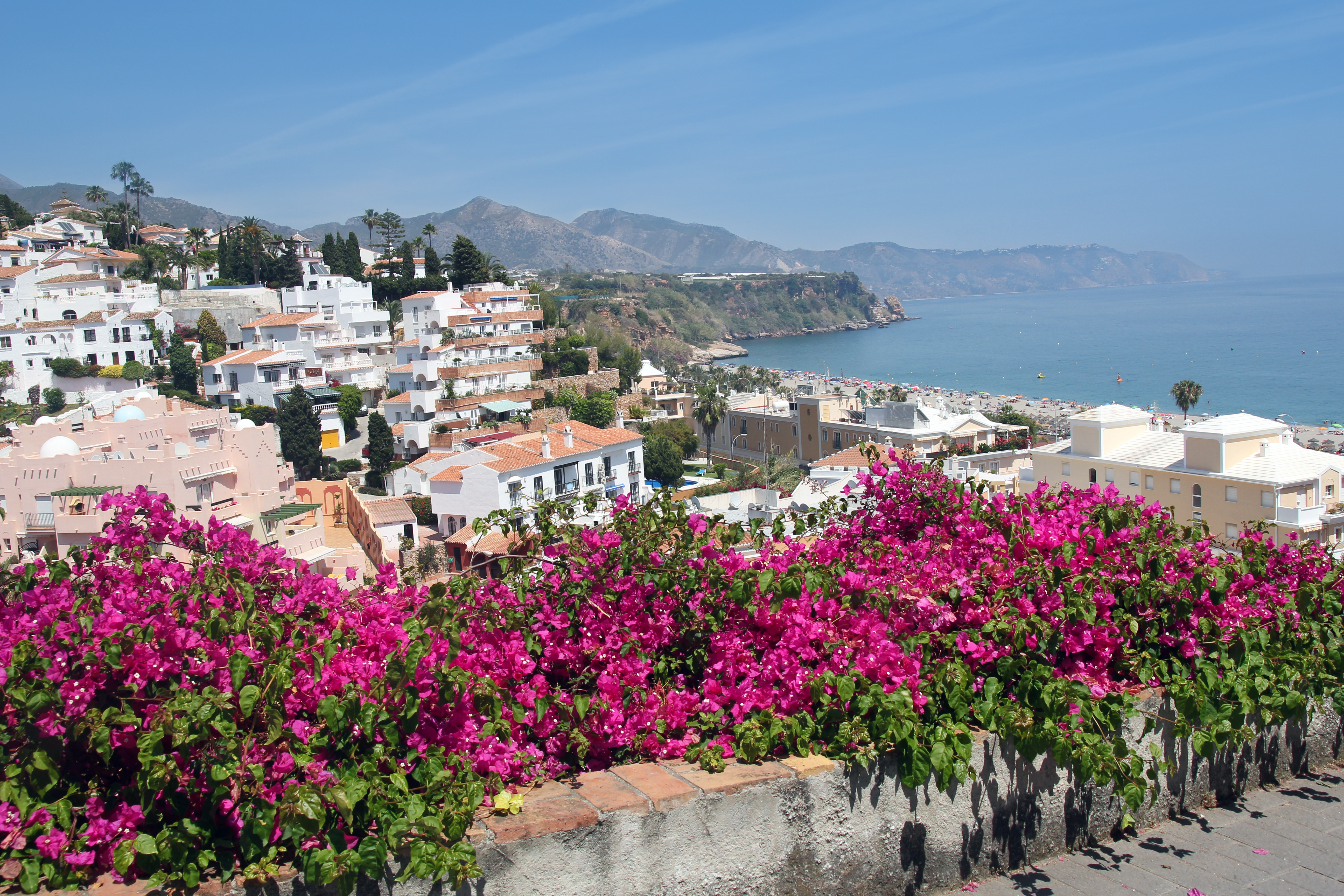 Skøn andalusisk kystby med lyserøde blomster, hvide huse og azurblåt hav