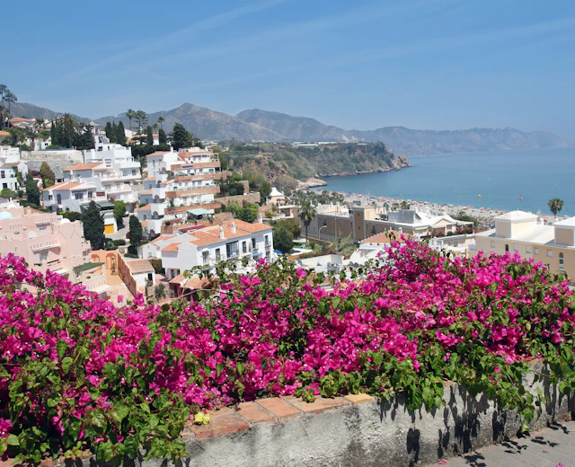 Skøn andalusisk kystby med lyserøde blomster, hvide huse og azurblåt hav