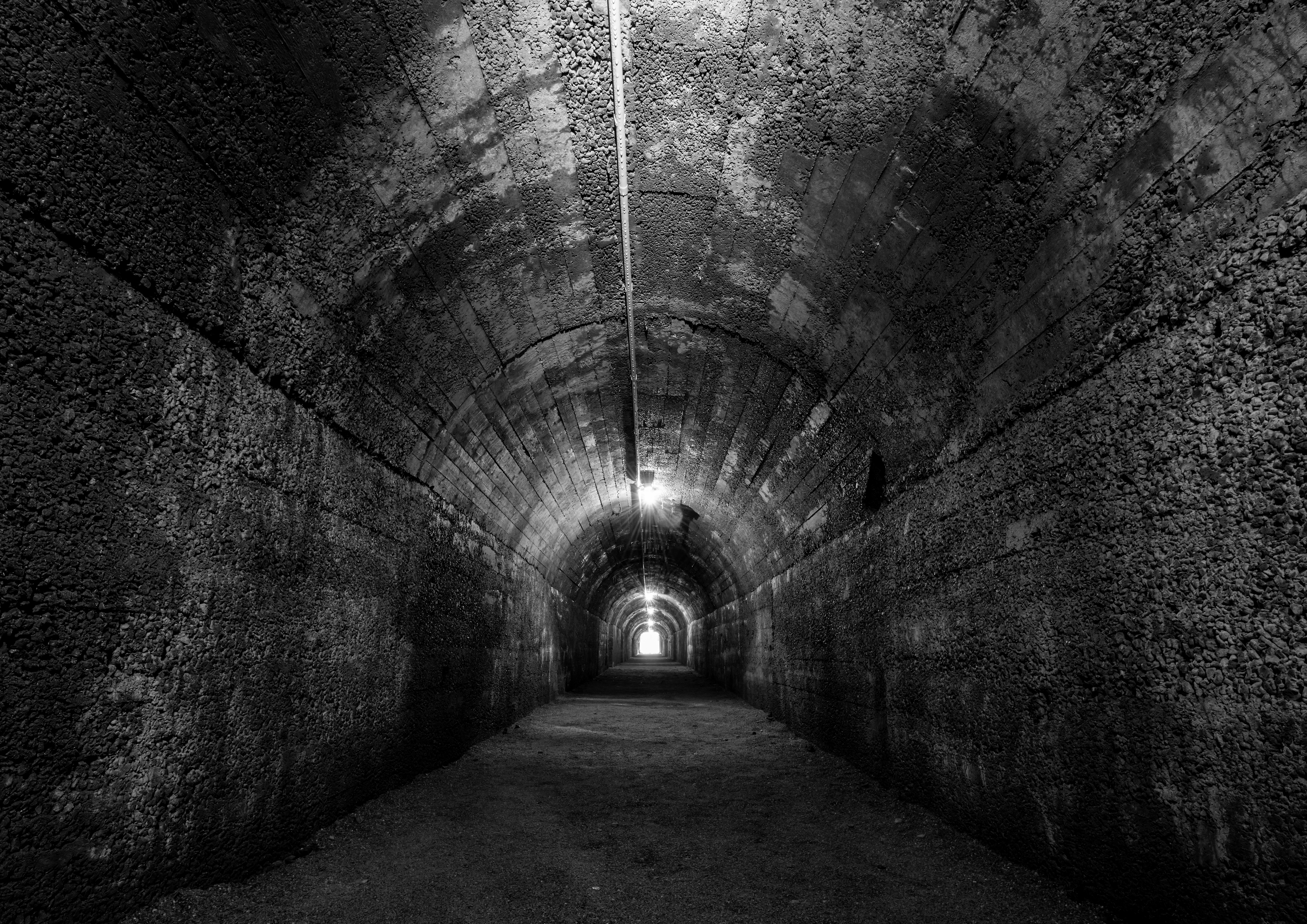 Forfalden og mørk bunkertunnel fra Anden Verdenskrig med stalaktitter, fugtige vægge og skræmmende stemning i sort-hvid