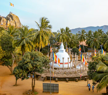 Fredfyldt buddhistisk tempelplads med hvid stupa og bønneflag i Mihintale nær Anuradhapura på Sri Lanka