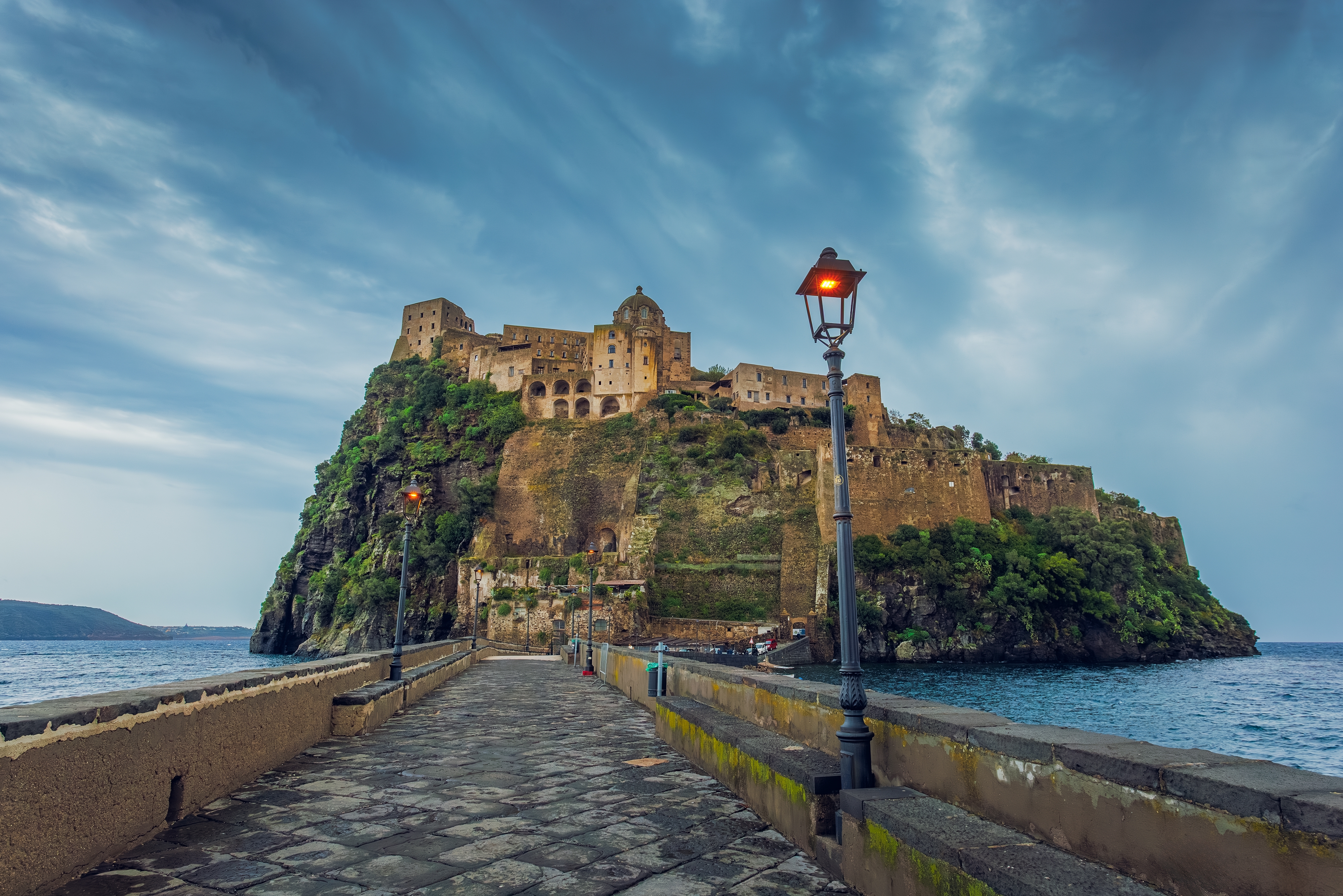 Historisk Aragonese borg på Ischia nær Napoli med stenbro over Middelhavet ved tusmørke