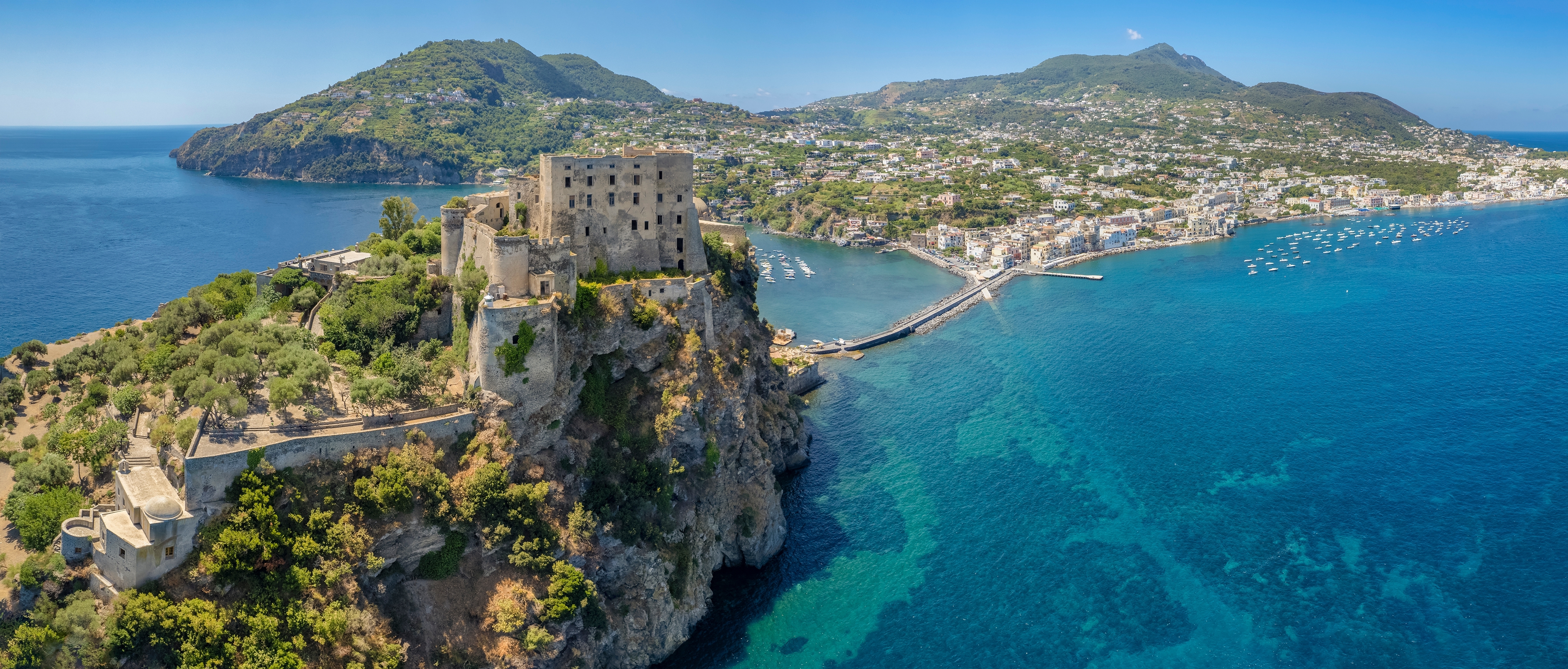 Panoramaudsigt over Castello Aragonese slot og fæstning på klippeø ved Ischia med turkisblåt vand