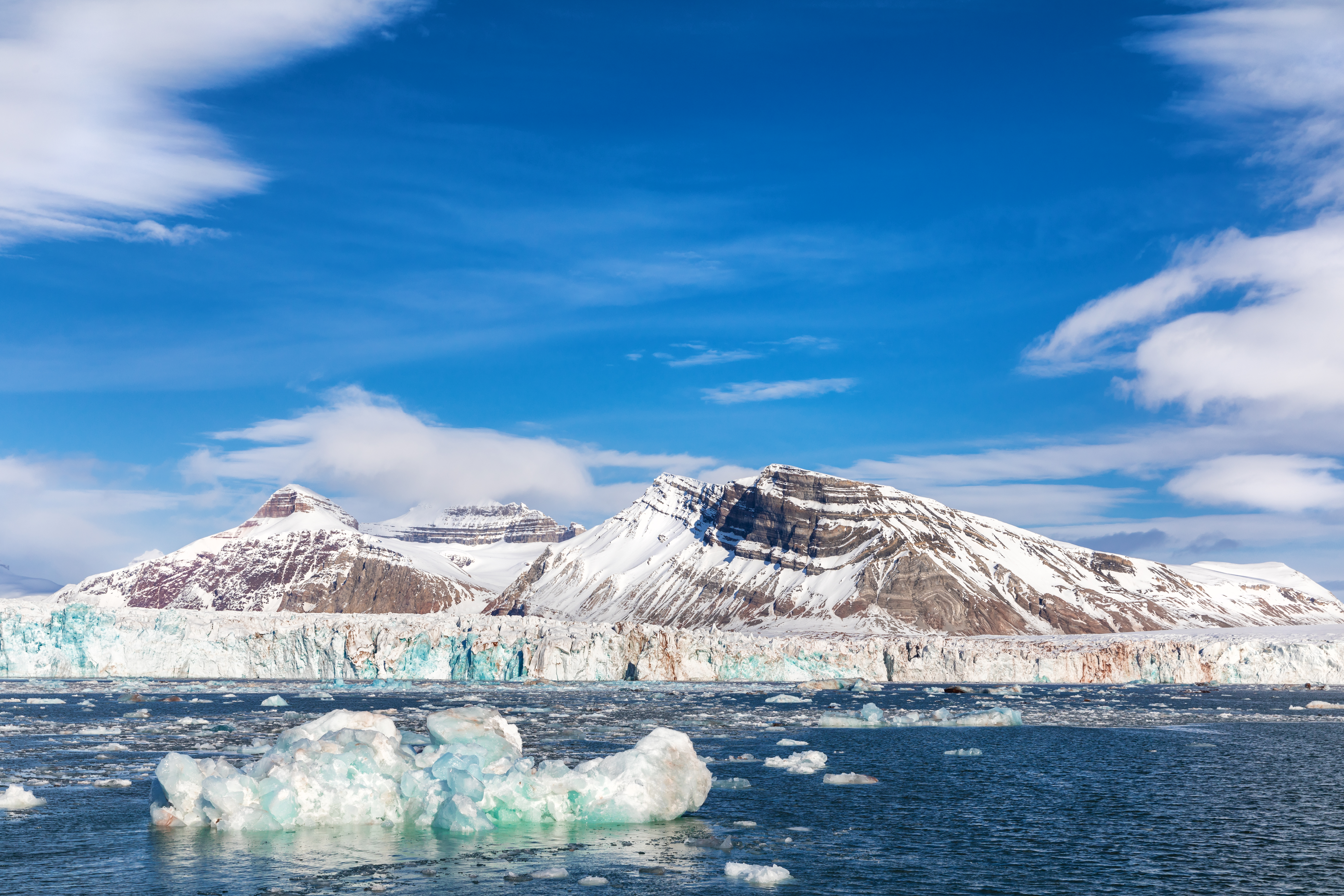 Fascinerende møde mellem is og bjerg i Kongsfjorden på Svalbard, hvor flydende isbjerge og gletsjere spejler sig i det kolde vand med de mægtige Tre Kroner bjerge som kulisse