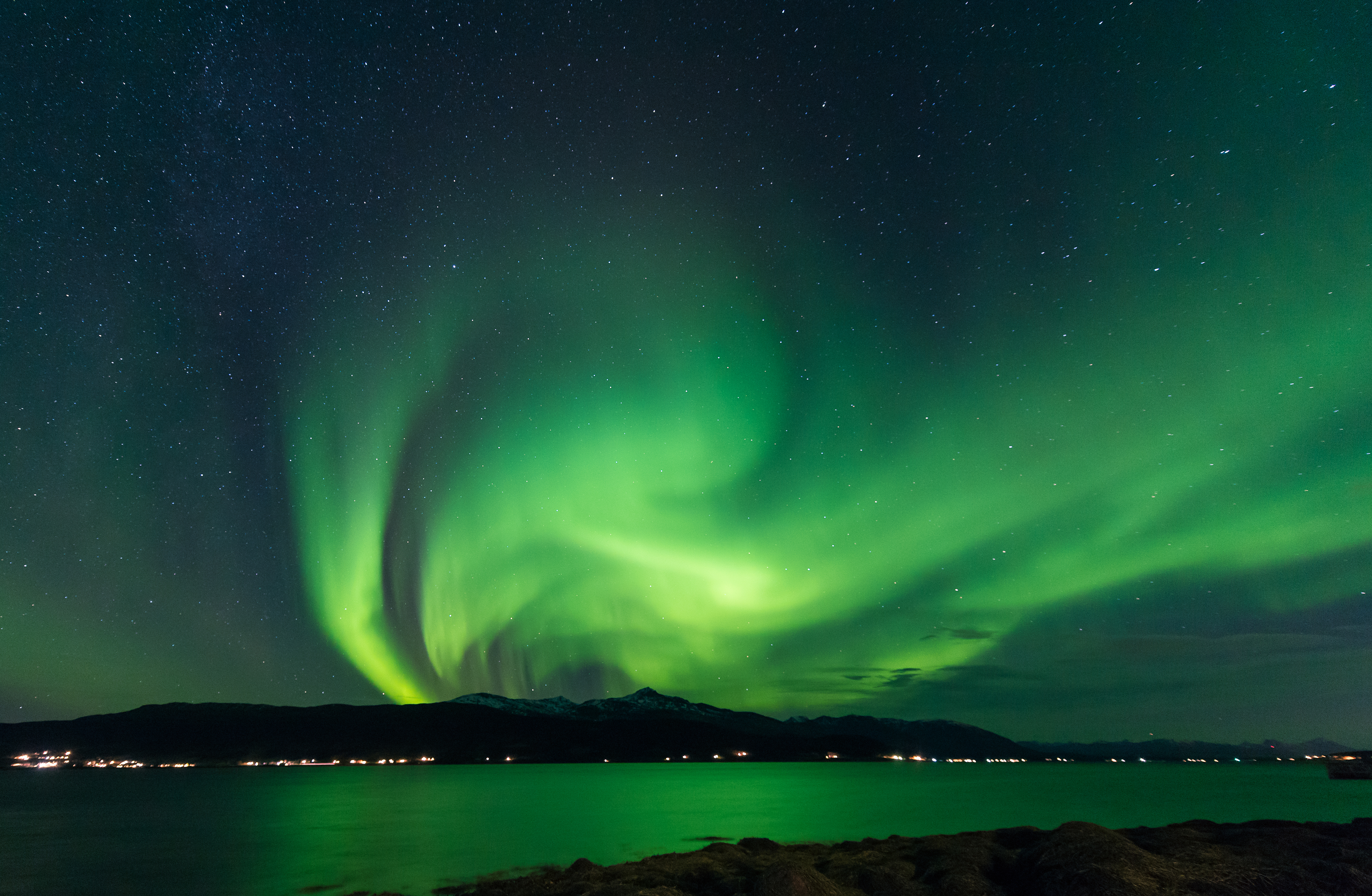 Imponerende nordlys aurora borealis i grønne nuancer over skandinavisk vinterlandskab med stjerner