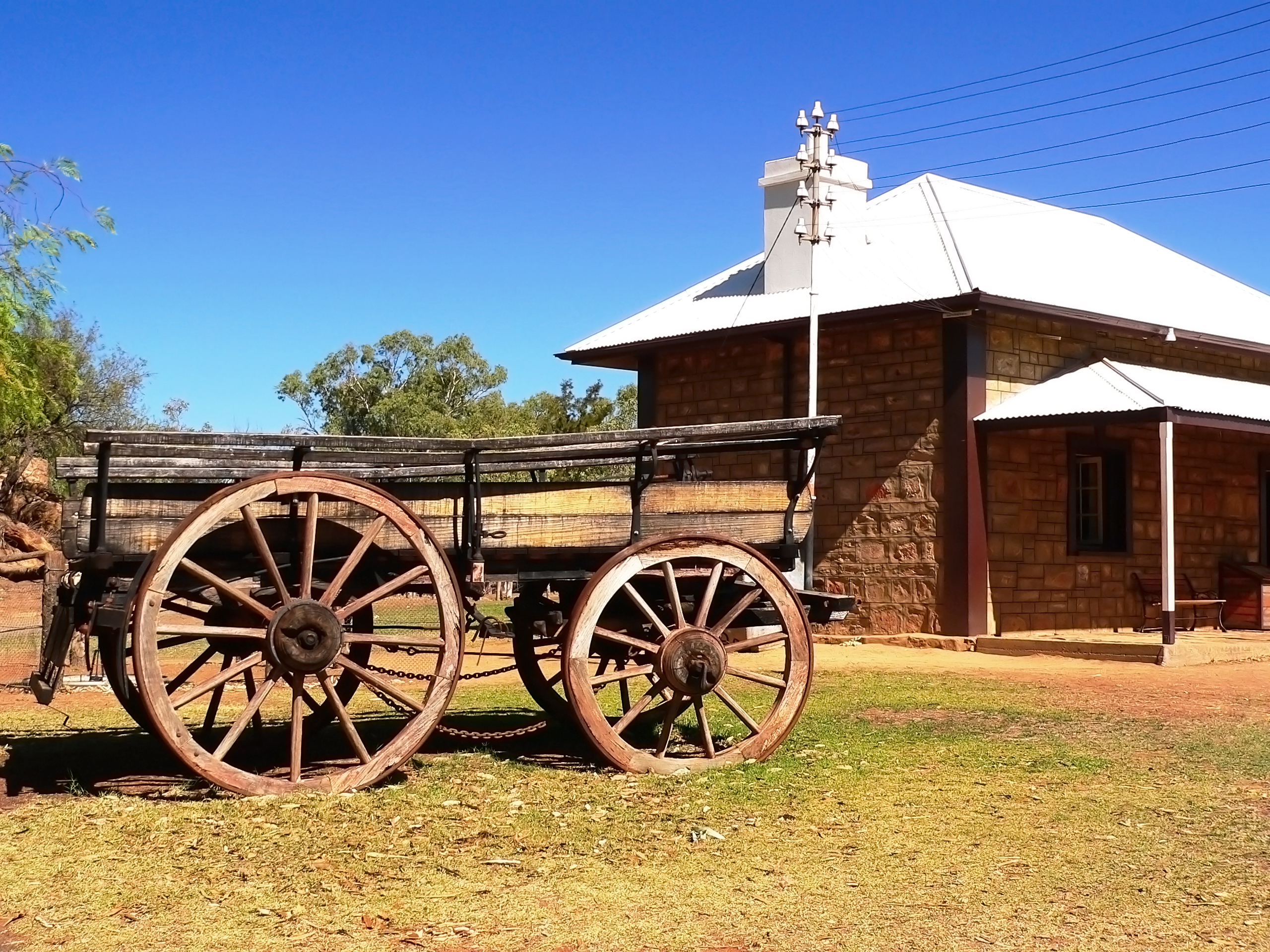 Alice Springs telegrafstation med gammel træhjulsvogn under blå himmel