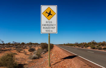Australsk nødbane vejskilt på øde landevej omgivet af tør buskvegetation