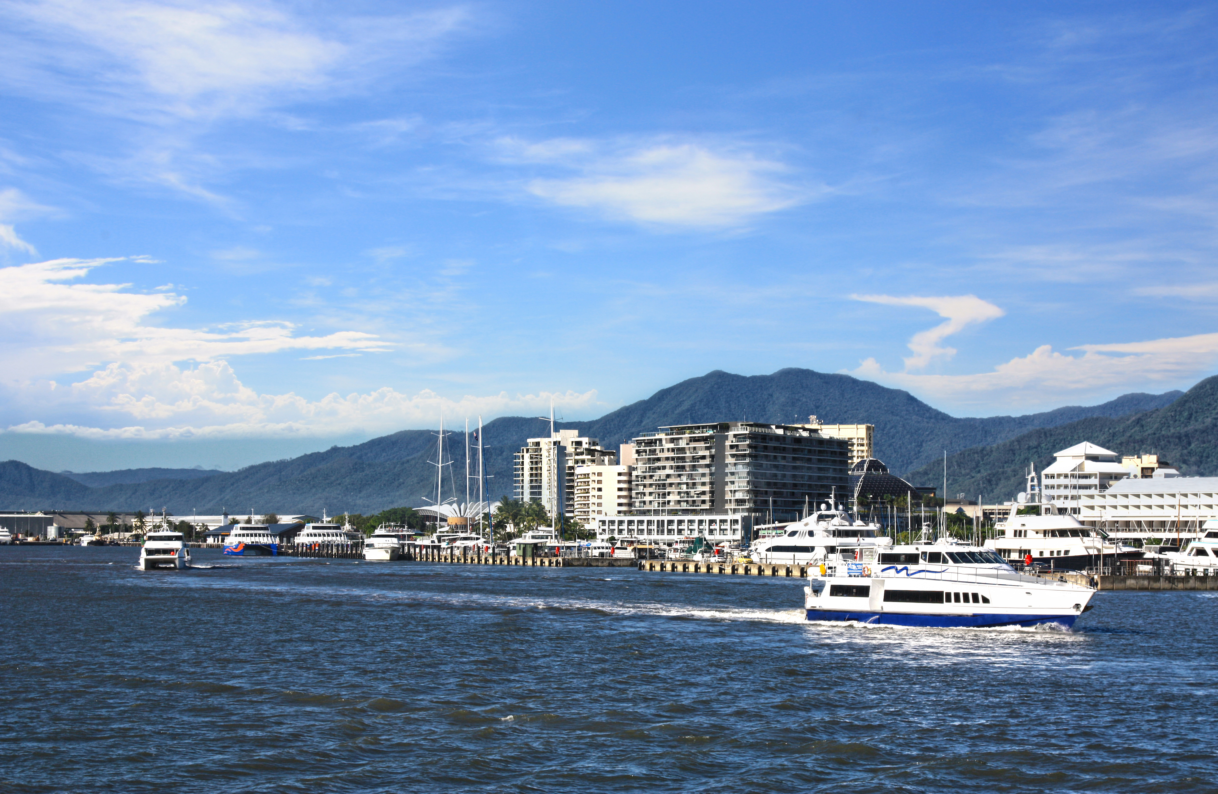 Smuk marina i Cairns Queensland med både og bjerge under blå himmel