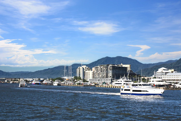 Smuk marina i Cairns Queensland med både og bjerge under blå himmel