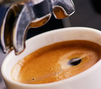 Autentisk italiensk espresso kaffe med crema hældes i elegant hvid kop