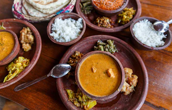Traditionelt Sri Lankansk thali måltid med aromatisk karry, ris, grøntsager og fladbrød i rustikke lerskåle