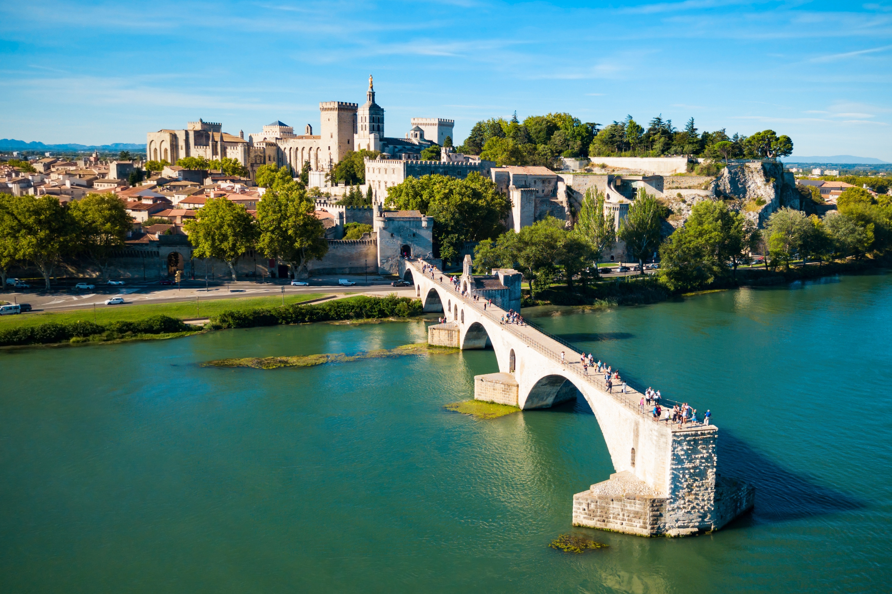 Betagende luftfoto af Pont Saint-Benezet broen og Rhône-floden med Avignons historiske centrum og Pavepaladset under klar blå himmel i Provence