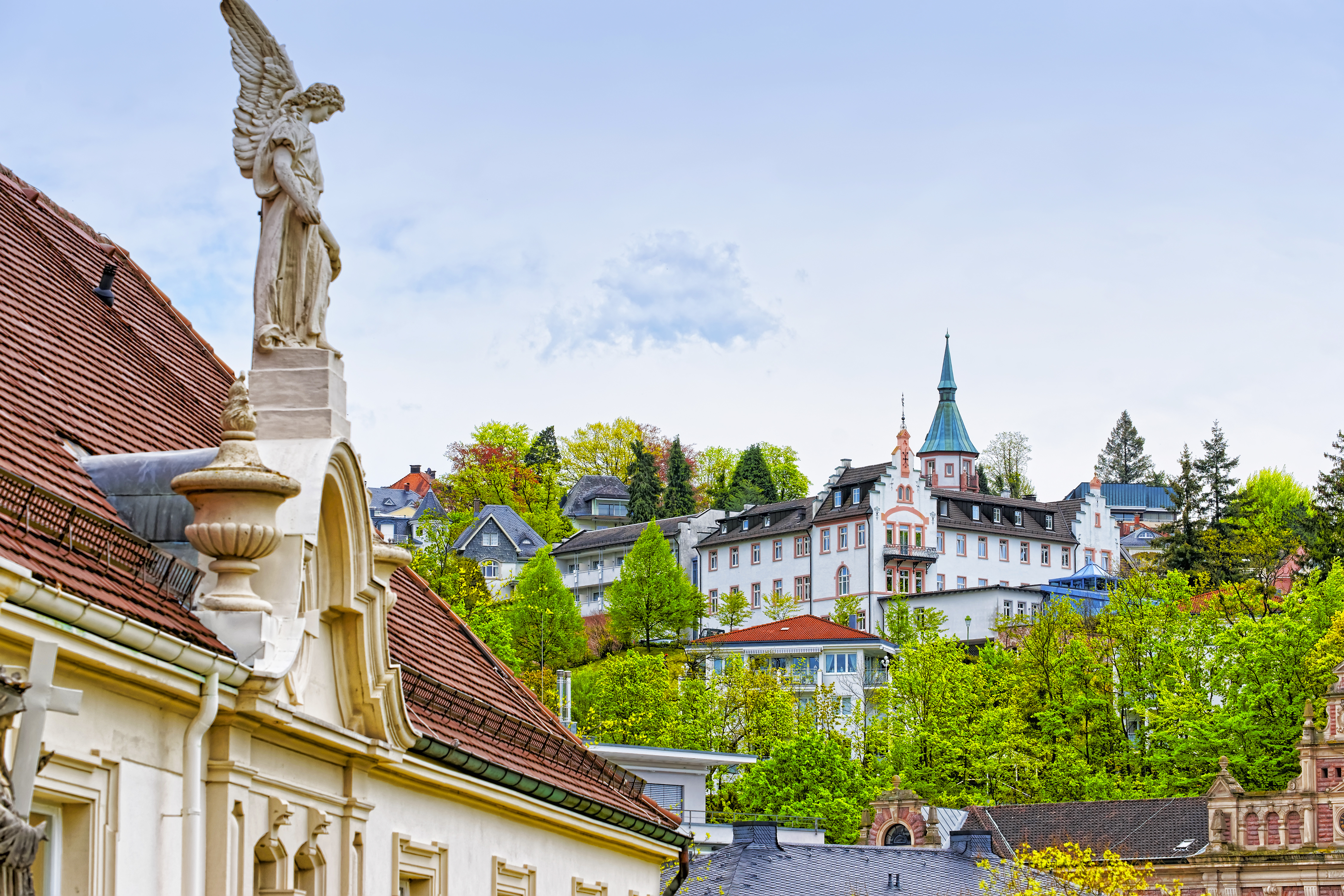 Majestætisk engleskulptur på tag i Baden-Baden med den berømte kurby og grønne bakker i baggrunden, Baden-Württemberg