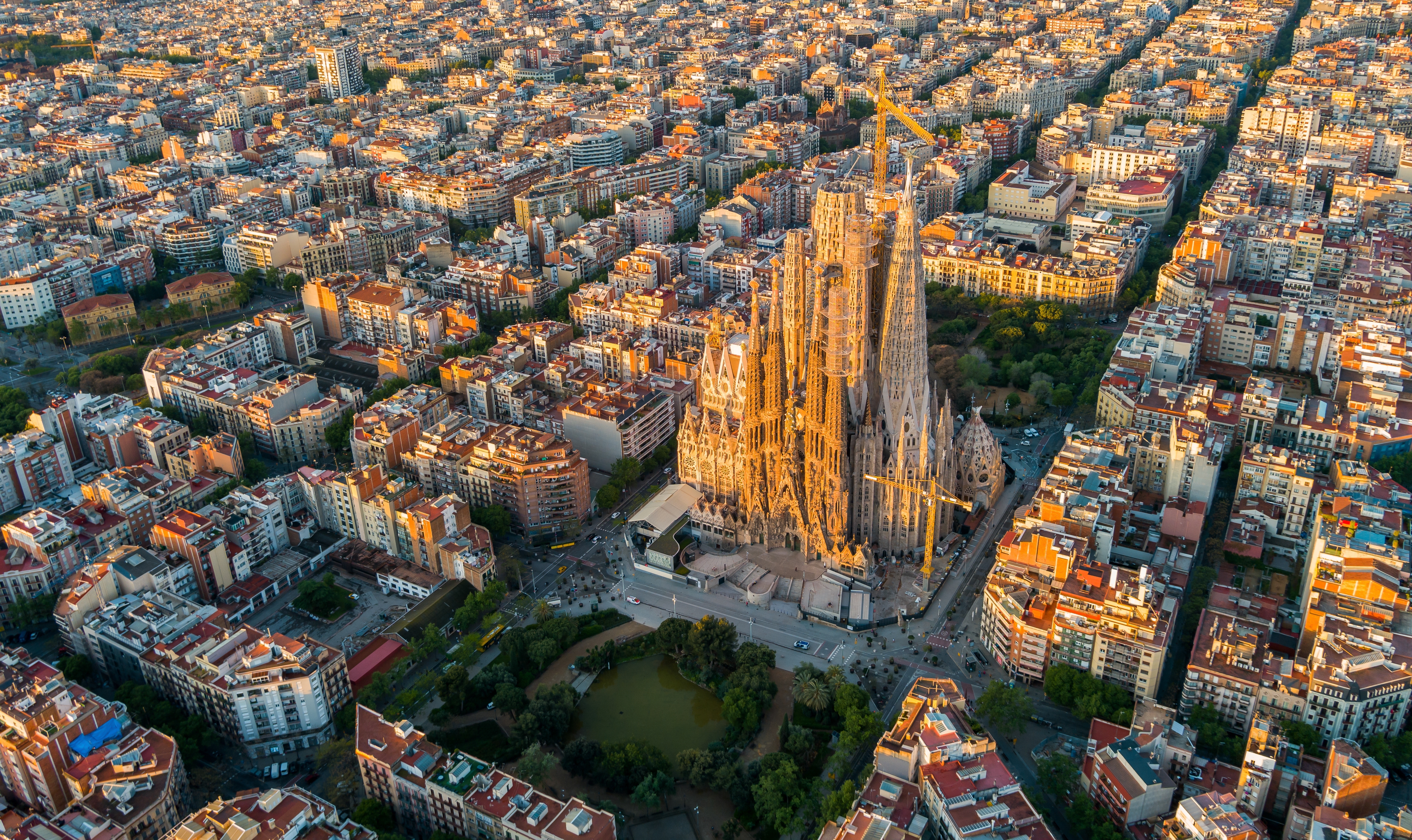 Luftbillede af Sagrada Família og Barcelonas Eixample-distrikt badet i morgenlys, Gaudís ikoniske katedral set fra oven