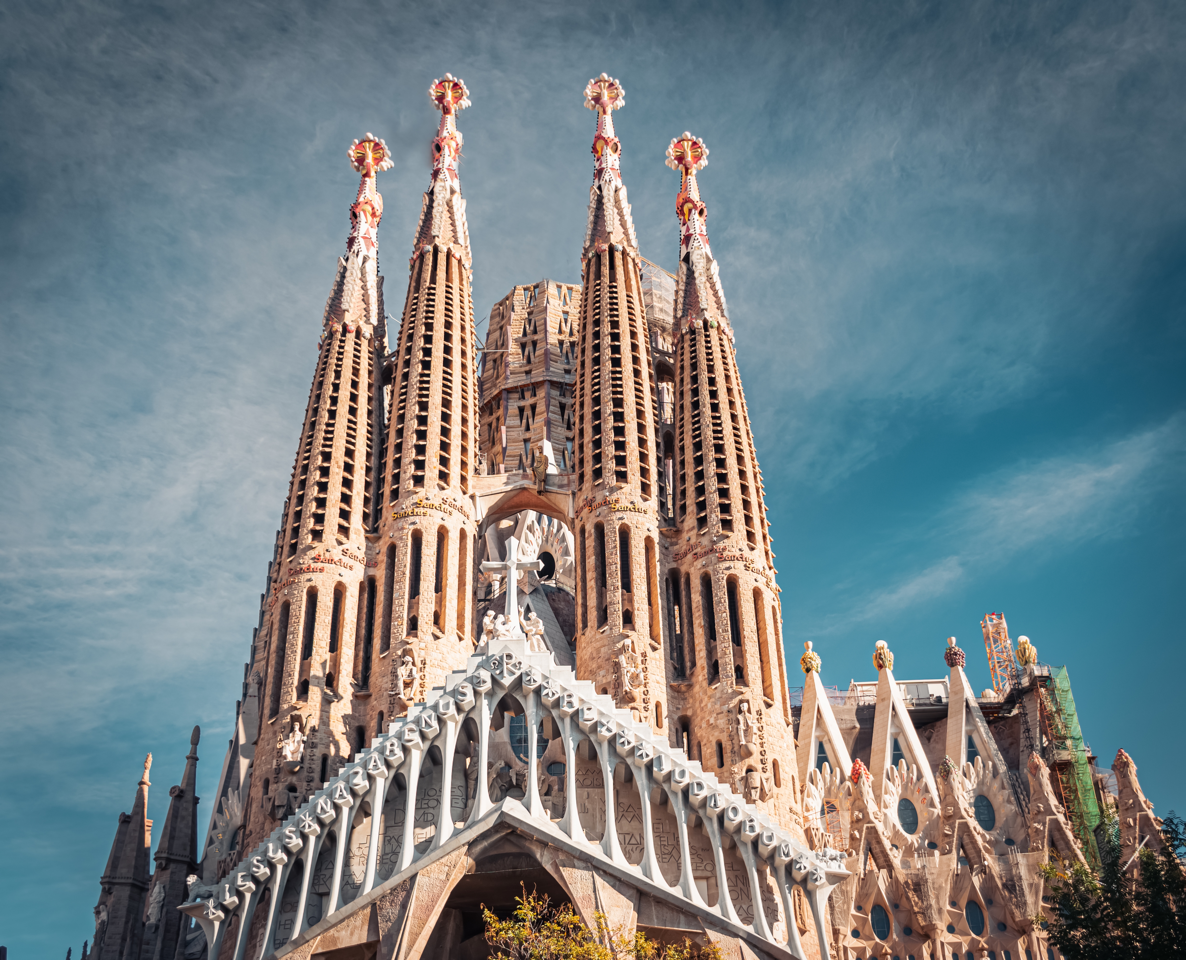 Sagrada Familia katedralen i Barcelona set nedefra med Gaudís unikke arkitektur, dekorative spir og smuk blå himmel i baggrunden