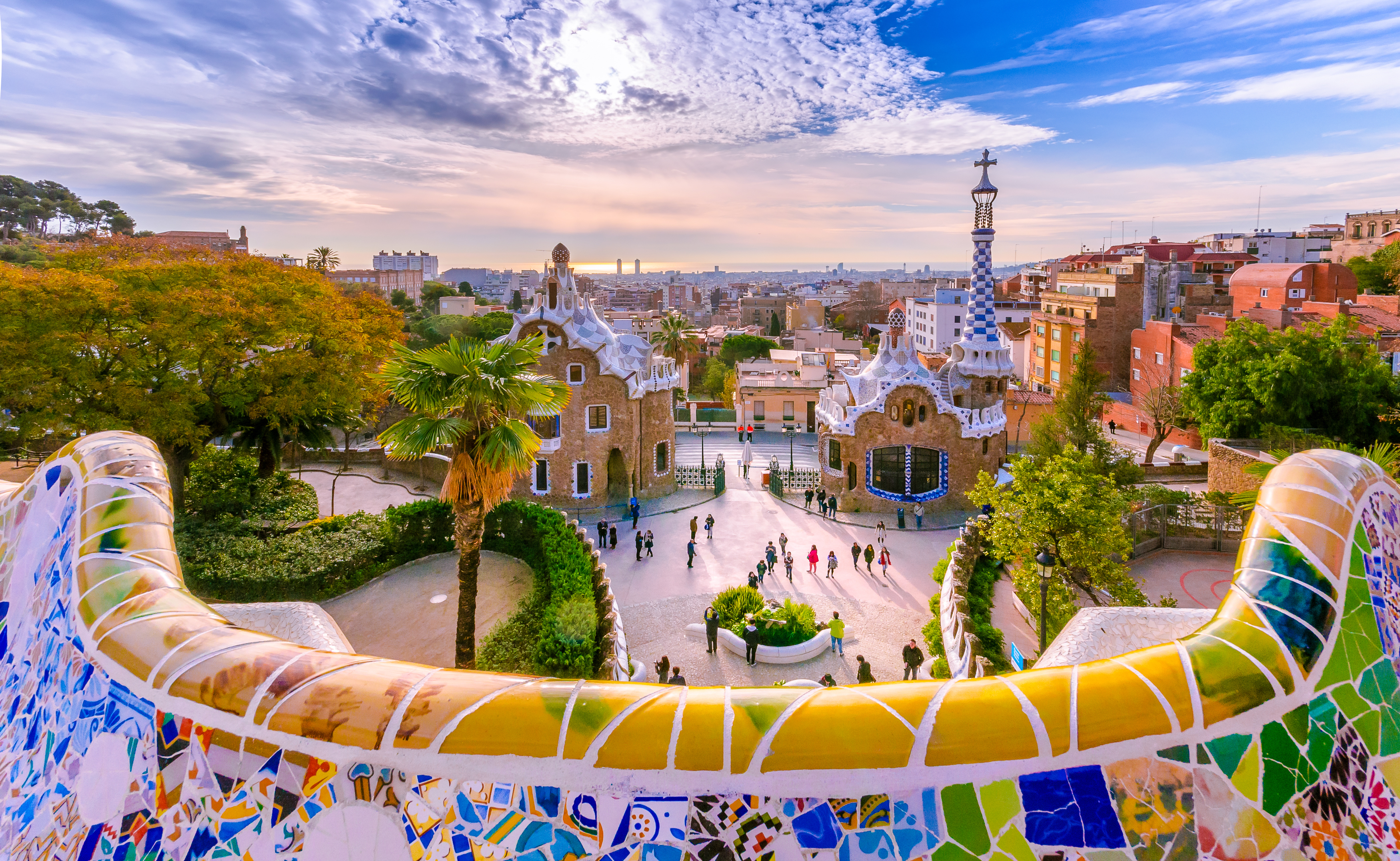 Turistattraktion Park Güell i Barcelona med farverig mosaik og byudsigt ved solnedgang
