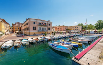 Traditionelle fiskerbåde og lystbåde i den charmerende havn i Bardolino, Italien
