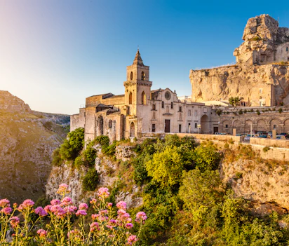 Den fascinerende stenby Matera med sine historiske Sassi-boliger og kirketårn oplyst af den gyldne solopgang i Syditalien