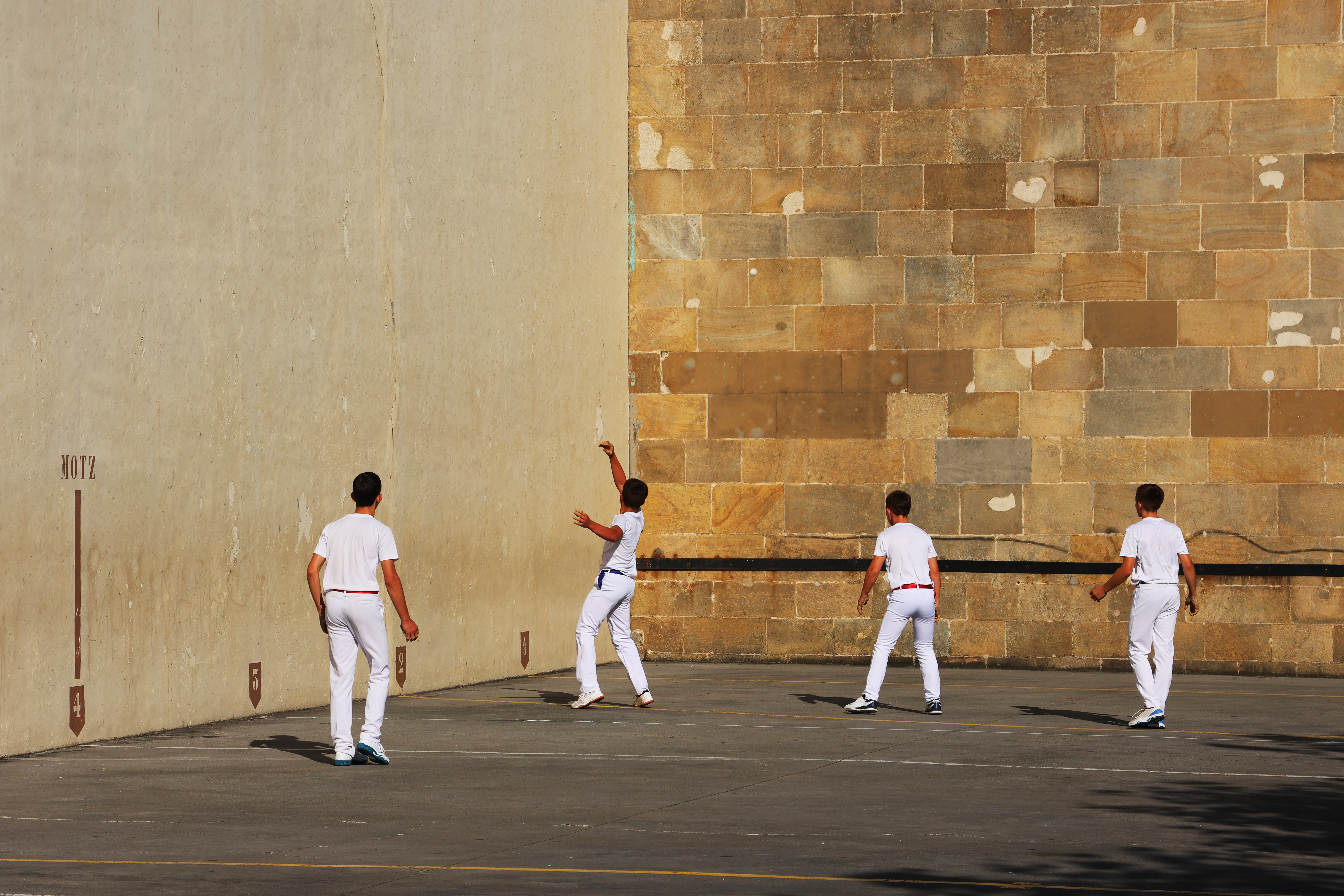Gruppe spillere dyrker traditionel baskisk pelota sport på stenmur bane i Euskadi