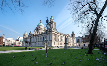 Belfast historiske rådhus omgivet af grøn park og træer i Irland