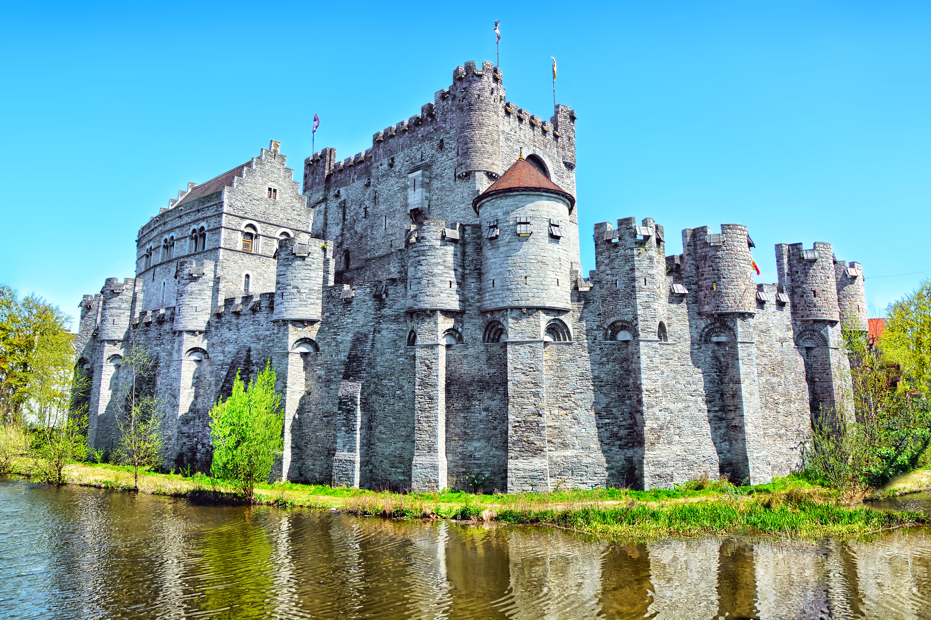 Det velbevarede middelalderslot Gravensteen med sine karakteristiske tårne og fæstningsmure ved kanalen i den historiske by Gent