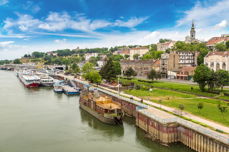Belgrade flodfront med gamle bygninger og turistbaade ved Donau