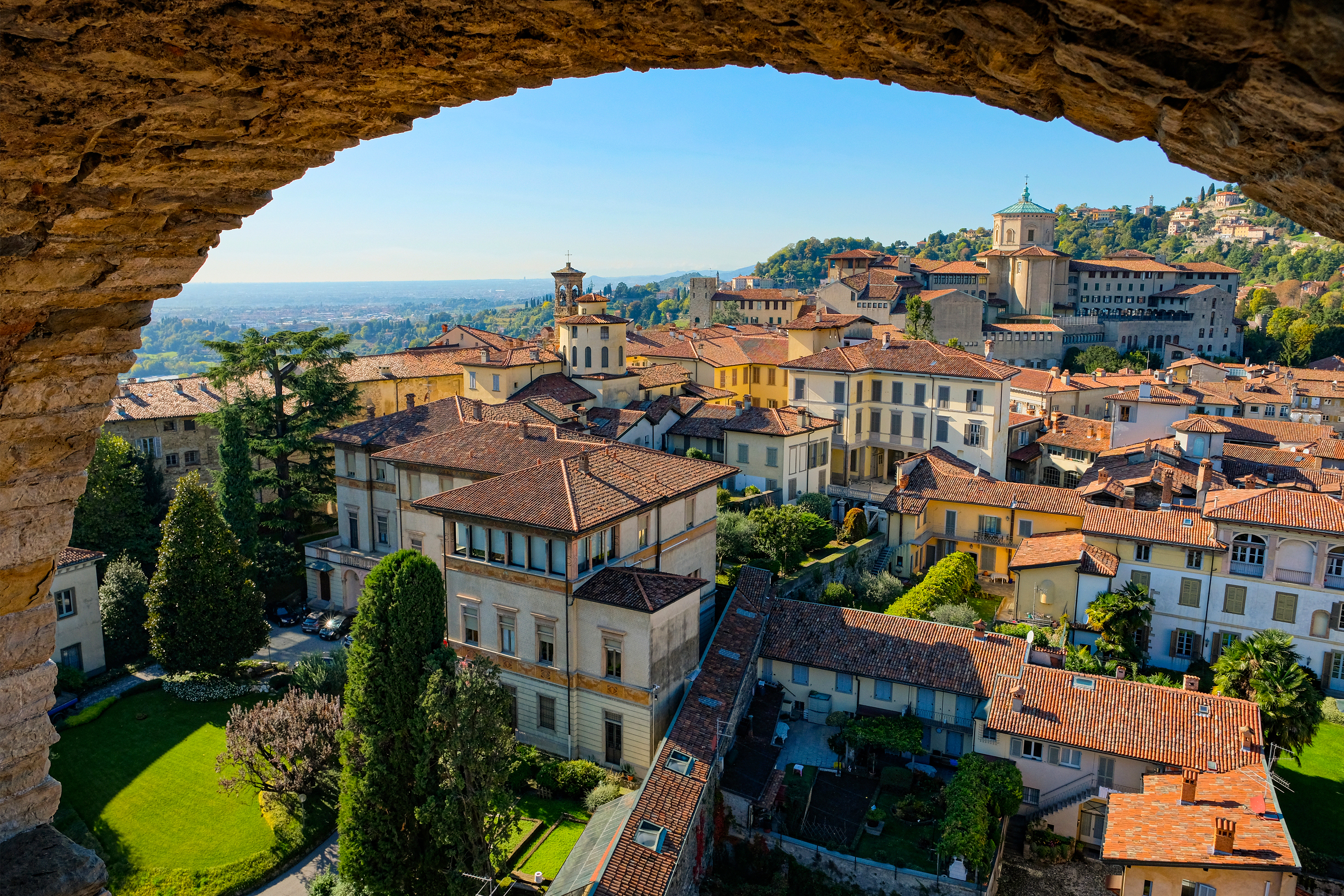 Malerisk udsigt over Bergamo Altas gamle bydel med historiske bygninger, terrakottatage og grønne bakker i Italien